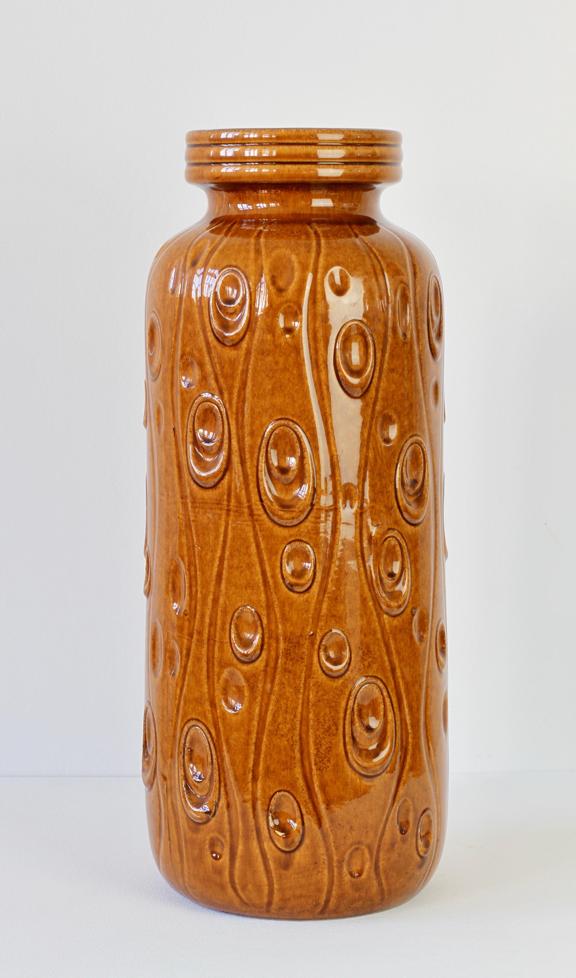 This tall collectable midcentury vintage floor vase was produced circa 1965 by the renowned producer of West German pottery - Scheurich Keramik. The vase features the 'Koralle' (Coral) relief pattern in a lovely amber brown color high gloss glaze.