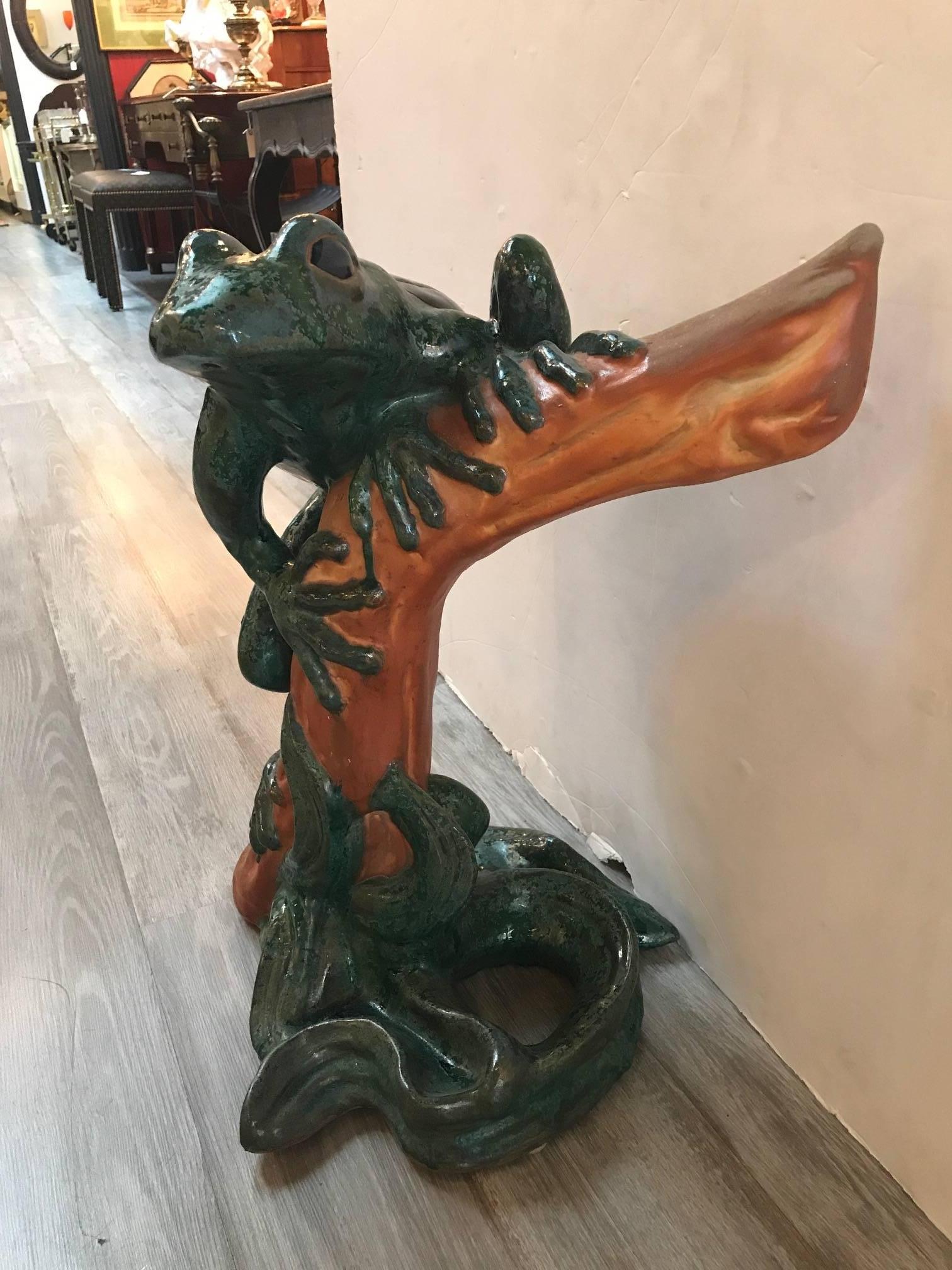 Vibrant glazed pottery sculpture of a frog made in Italy in the mid-20th century. The posed frog, on wood motif branch with unusual fire glazed green and blue finish.