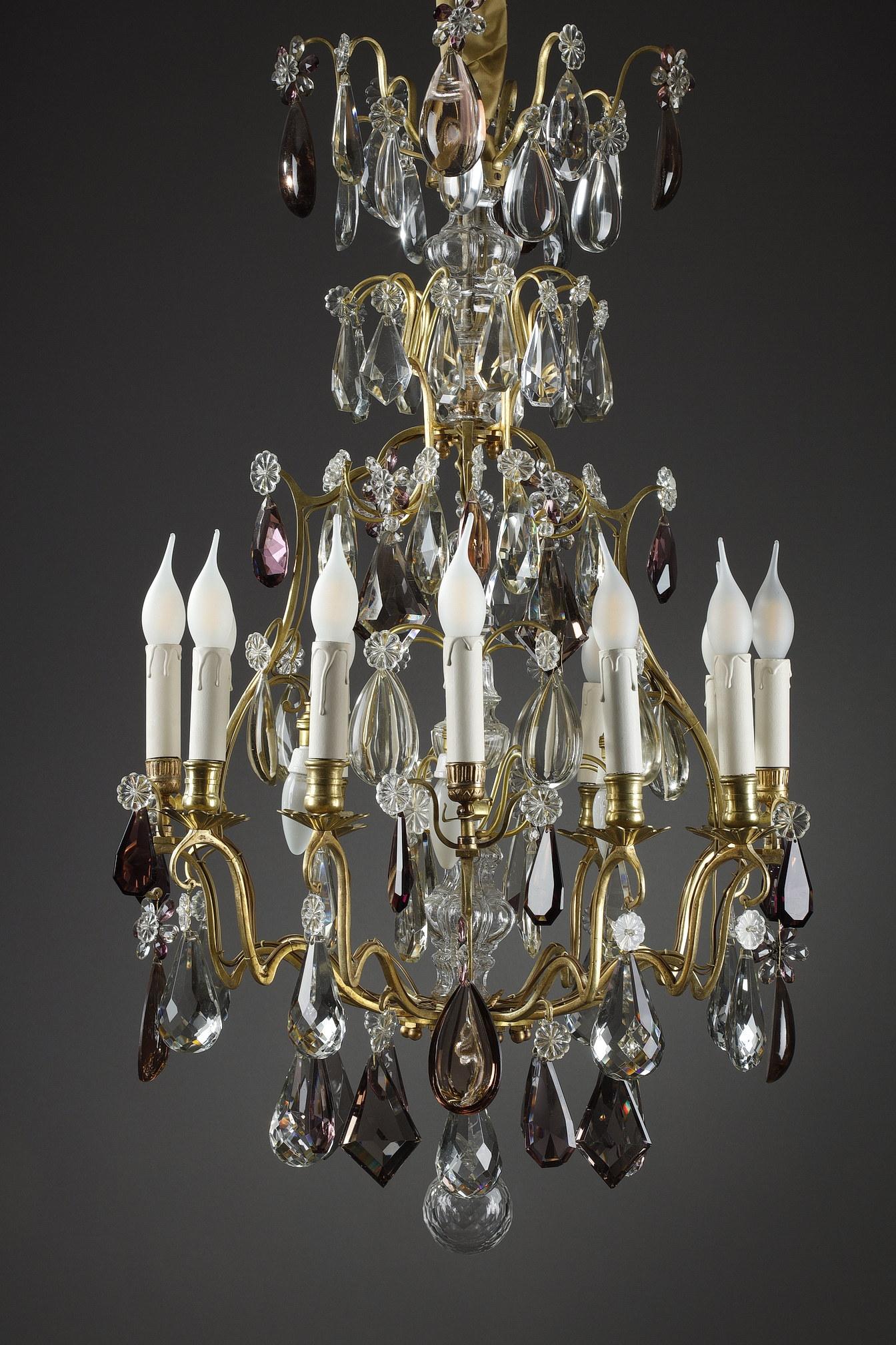 A large sixteen lights chandelier in white and amethyst crystal. It has twelve arms of lights at the edge and four inverted lights in the central part. This chandelier is composed of six rows of cut pendants, rosettes and half-pears with a