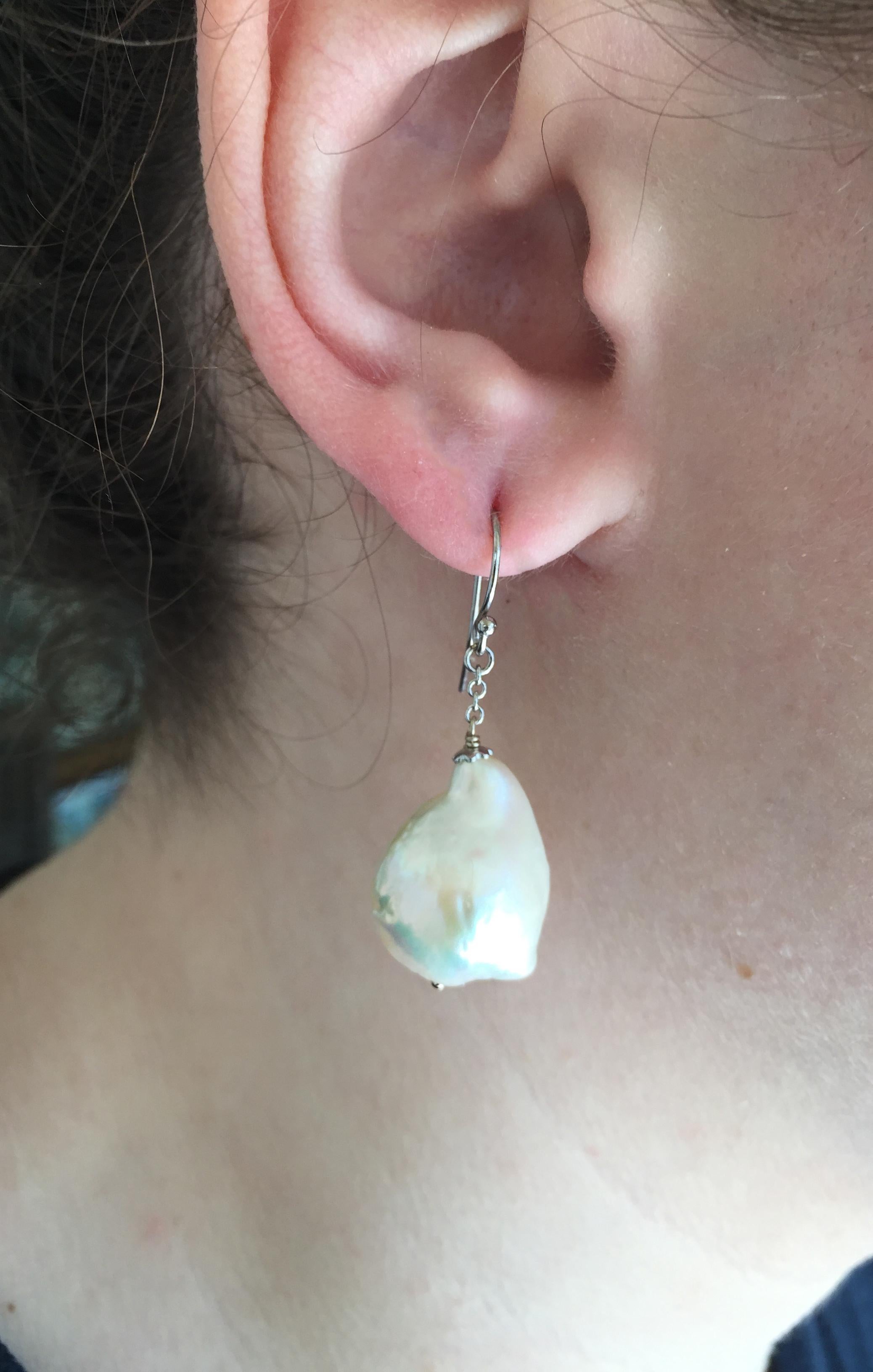 These large white baroque pearl dangle earrings with 14k white gold chain and hook are stunning. The tear drop white baroque pearl is effervescent and shimmers in the light. Highlighting the pearl's beauty is a 14k white gold chain and hook. The