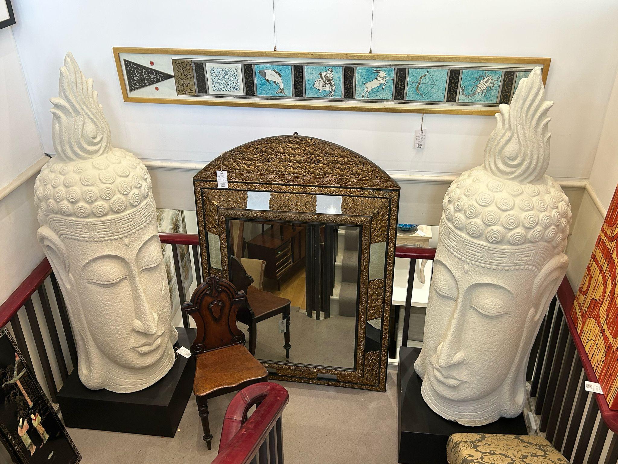 A large white resin head sculpture of a buddha head which brings a profound sense of calm to any space. Sat atop a black stand, the sculpture makes a great statement piece with its detailing and tranquil expression.

The clean white offers a