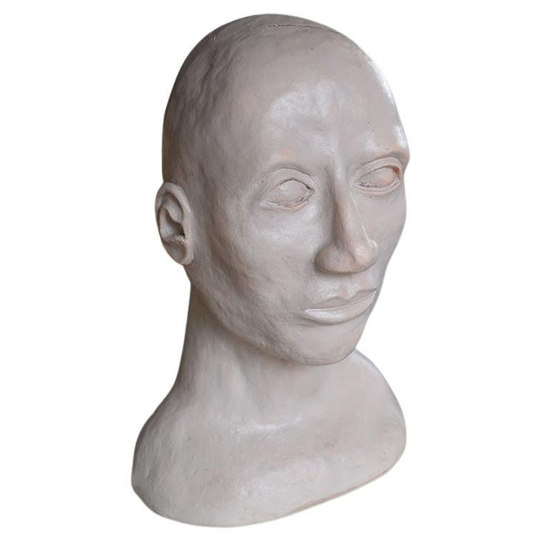 A large hand-sculpted bust of a man. Created from white clay, this piece is life-size and depicts a man who stares off into the distance. 

Measures: 14.75