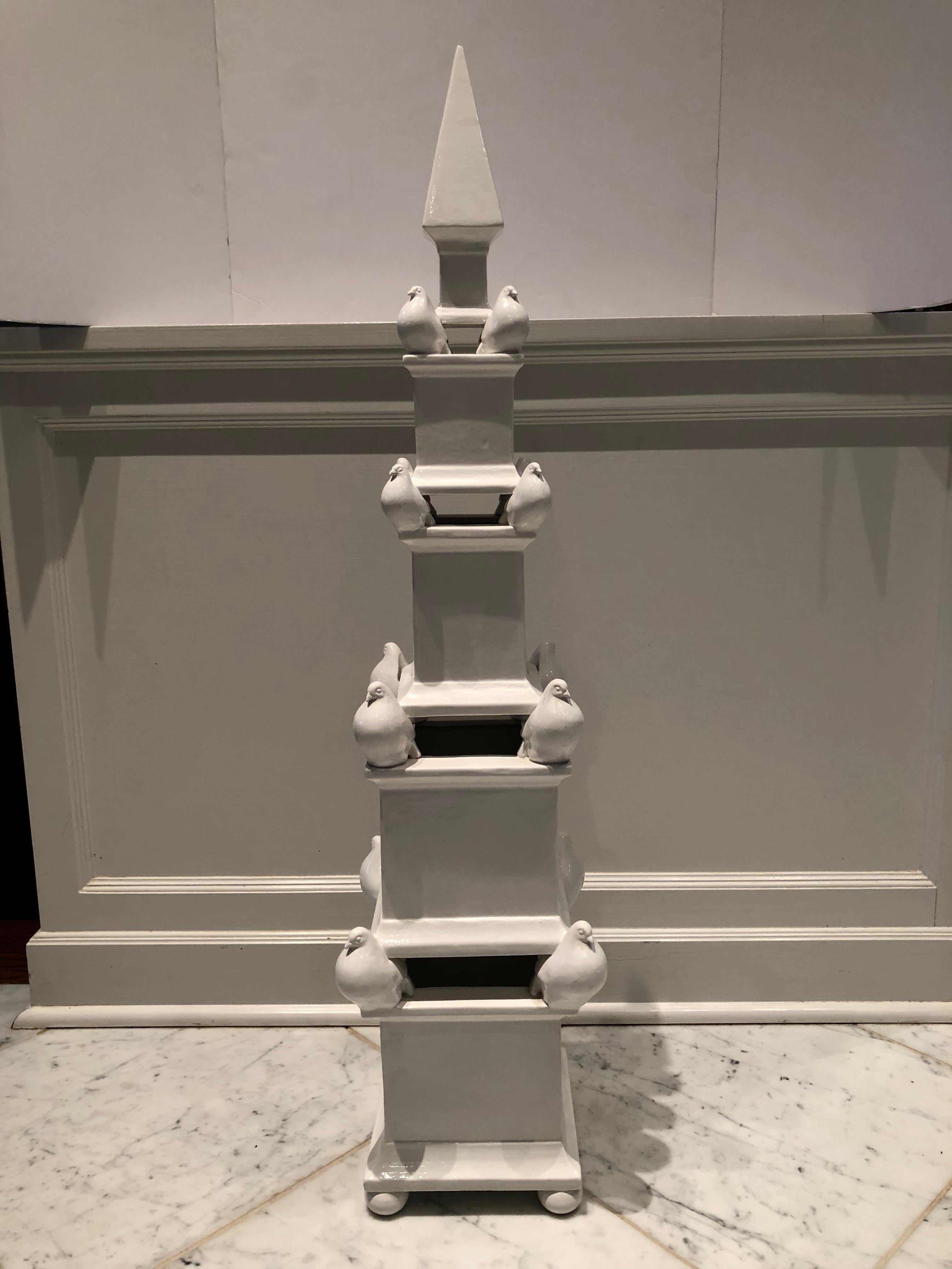 A striking and lovely quite large white ceramic obelisk with doves perched at each corner. Comprised of two pieces with pretty ball feet.  Signed on bottom Made in Italy for Gump’s.  .