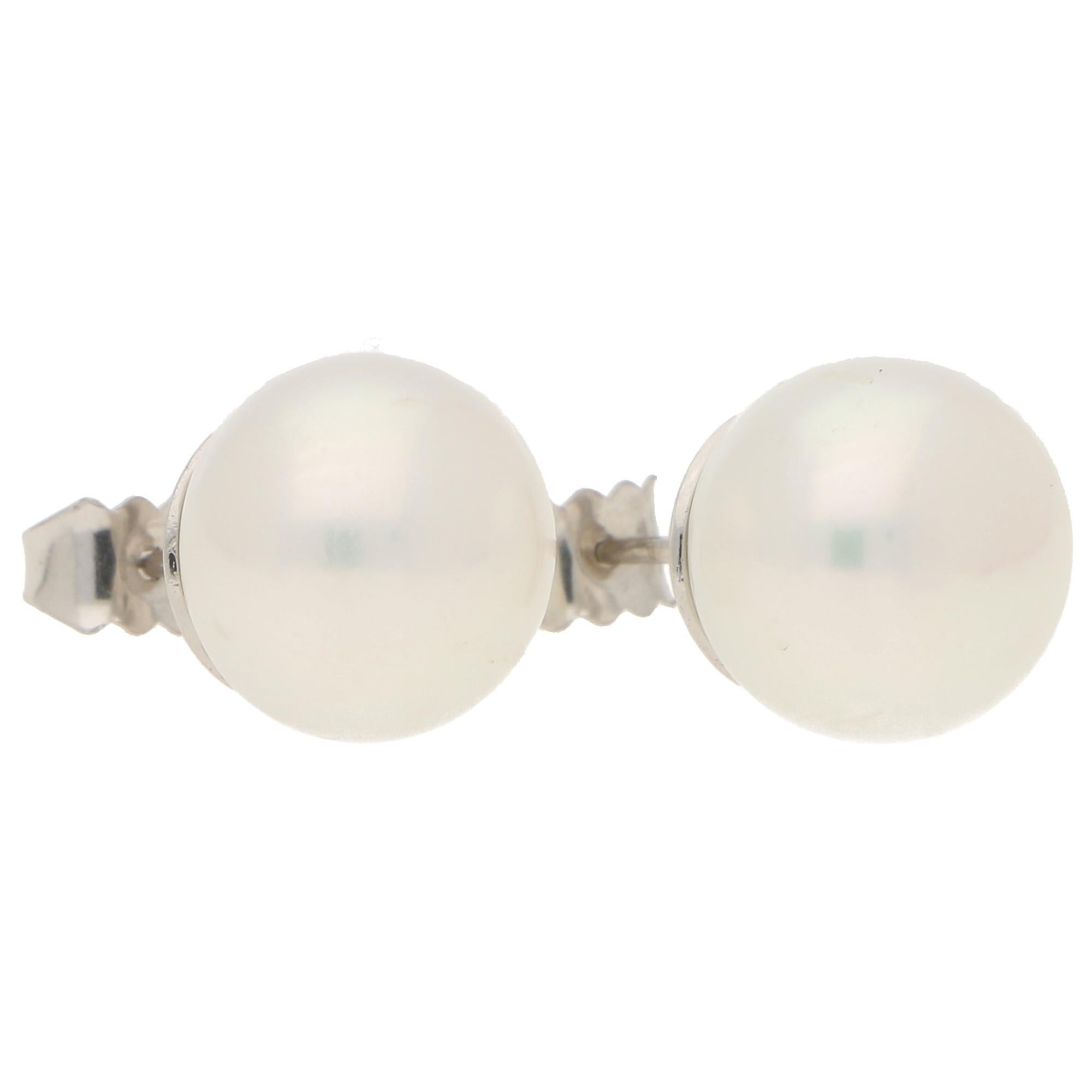  An elegant pair of large freshwater pearls set in 18k white gold. 

Each earring features a lustrous freshwater button pearl of a white colour with a pinkish overtone. 

he earrings are secured to reverse with a post and butterfly fitting. 

For