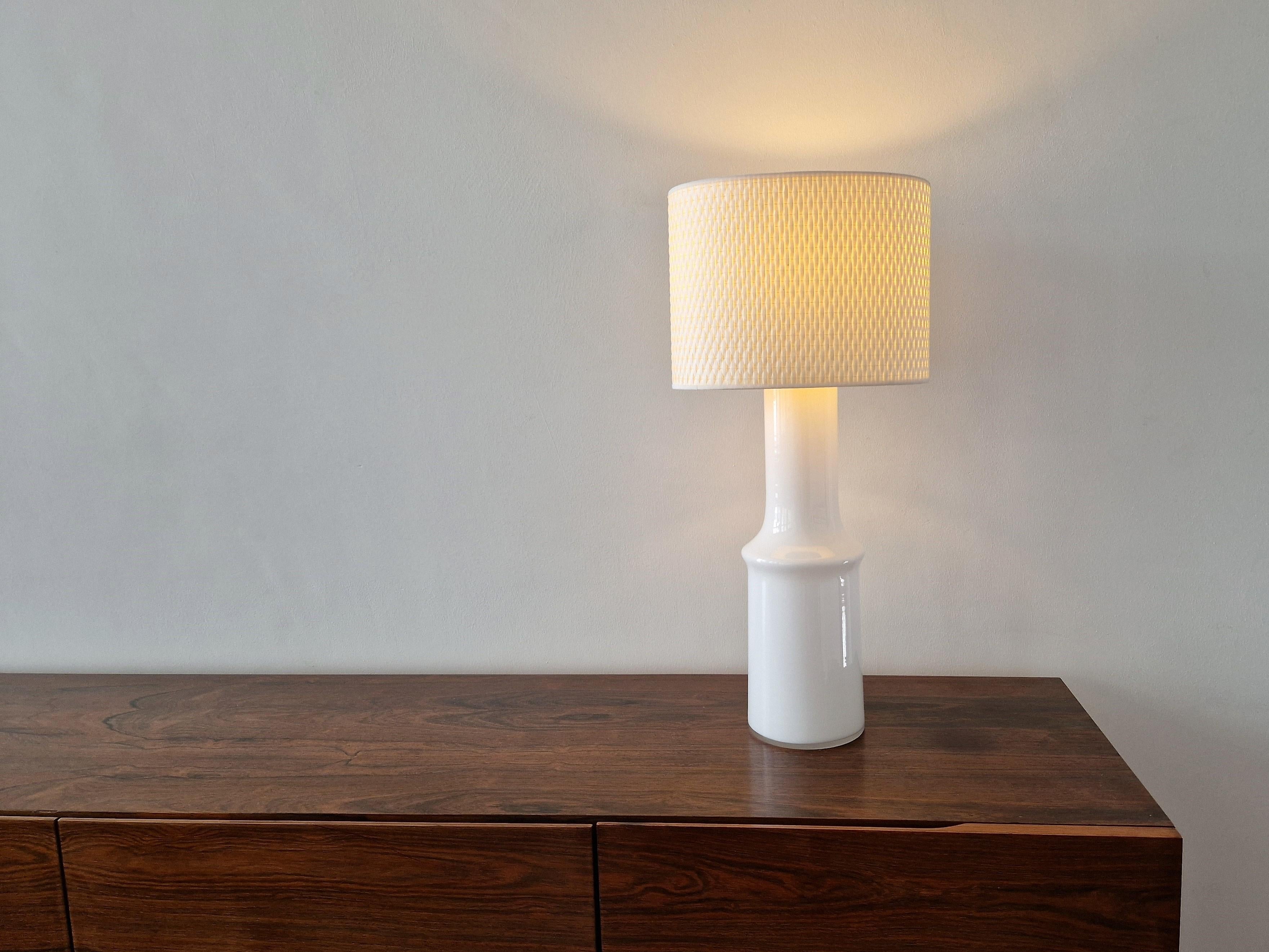 This large vintage table lamp was made by Hyllinge Glasswork in Sweden in the 1960's or early 1970's. A design by Gert Nyström. It is made of thick white colored glass, with a clear round glass top. The lamp is in a very good condition with hardly