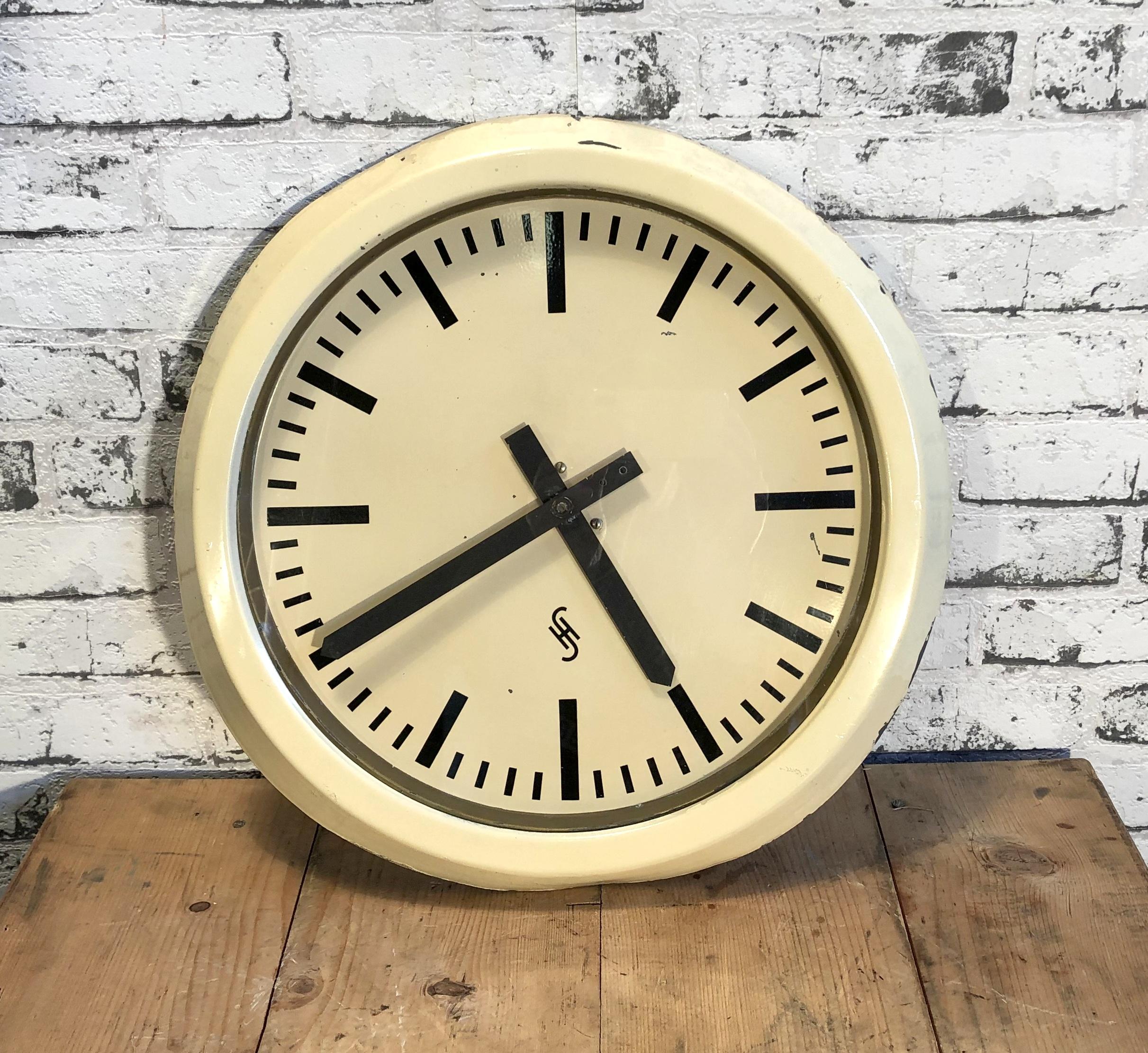 This large wall clock was produced by Siemens and Halske in Germany during the 1950s. It features a white metal frame, aluminum dial, and a clear glass cover. The piece has been converted into a battery-powered clockwork and requires only one