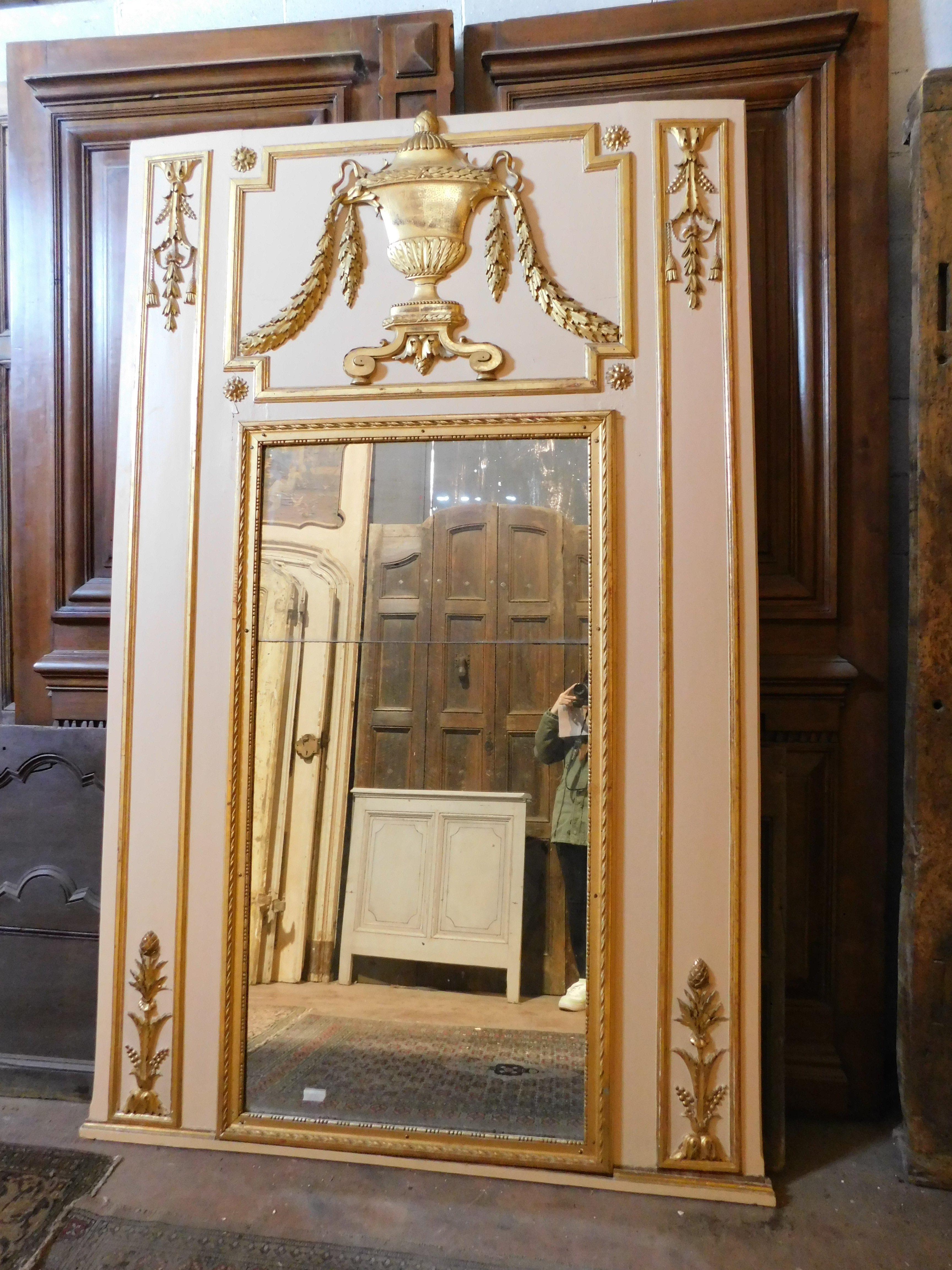 Grand miroir ancien en bois laqué blanc, à décor de coupes dorées et sculptées de festons dans la partie supérieure et de fleurs dans les montants, très haut, probablement né au-dessus d'une console ou au-dessus d'une cheminée, maintenant aussi