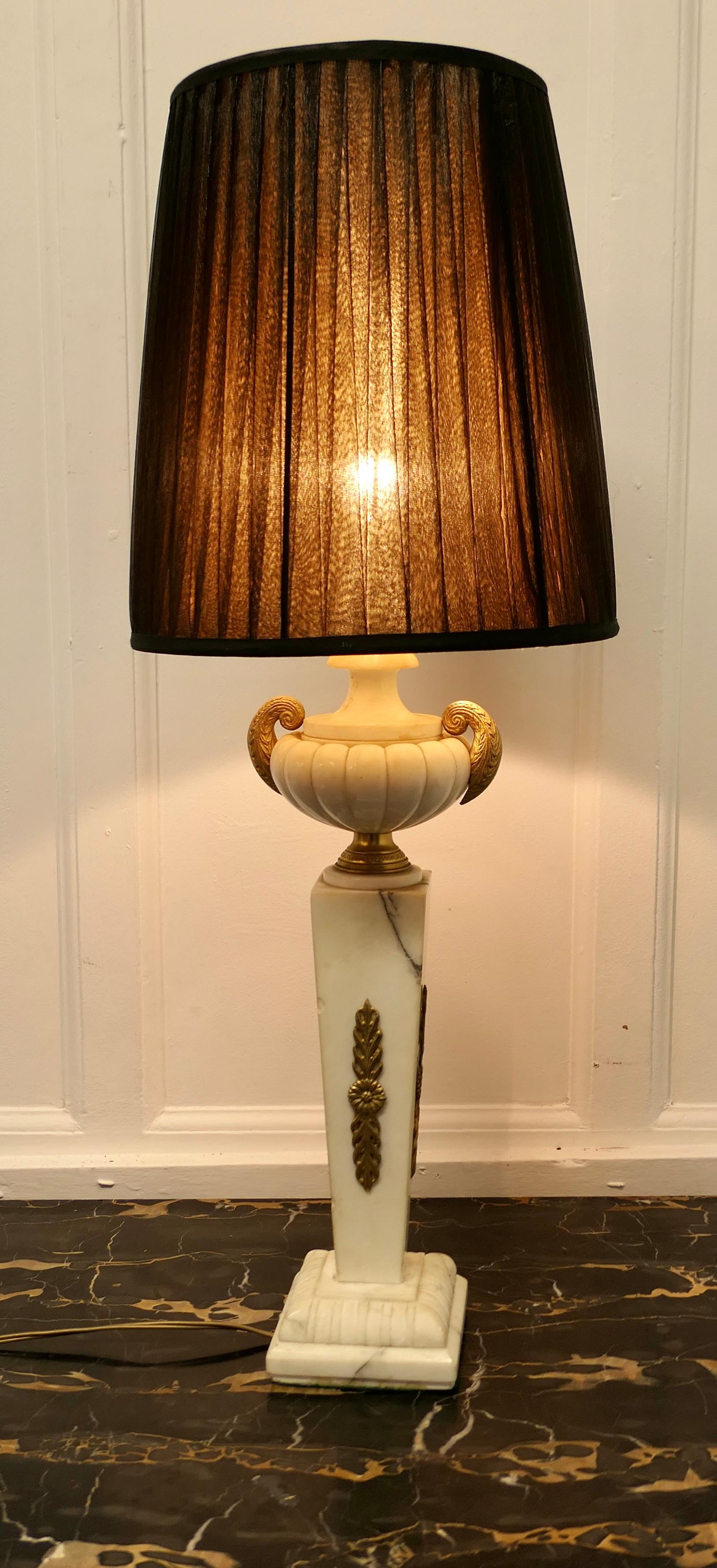 Large white marble classical Greek style table lamp

This is a very heavy piece it is made in solid marble with ormolu mounts, the lamp is set on a rectangular pillar with an urn at the top and a little grey marbling 
This is a very attractive