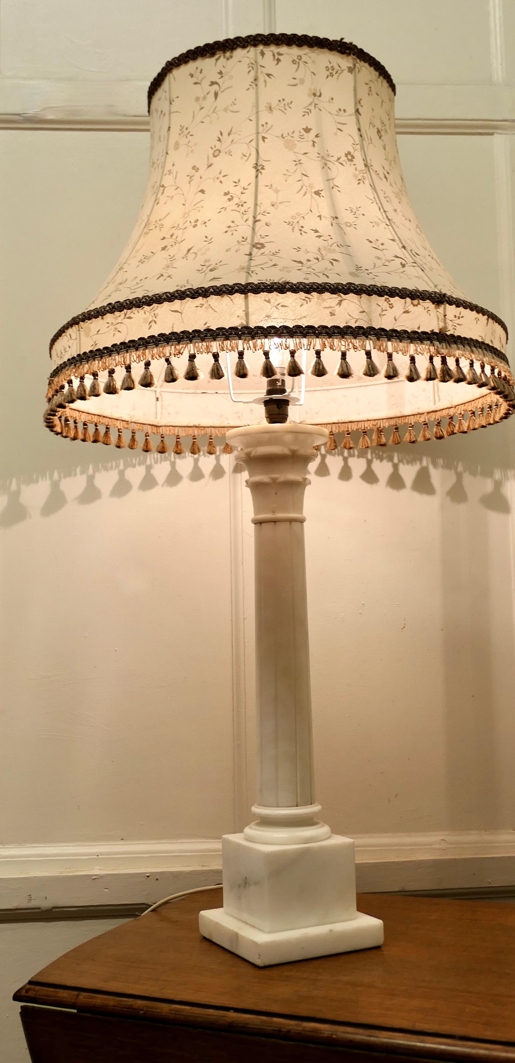 Large white marble corinthian column table lamp

This is a very heavy piece it is made in solid marble, the lamp has a single reeded marble corinthian style column with fine grey marbling it is set on a square stepped base
This is a very