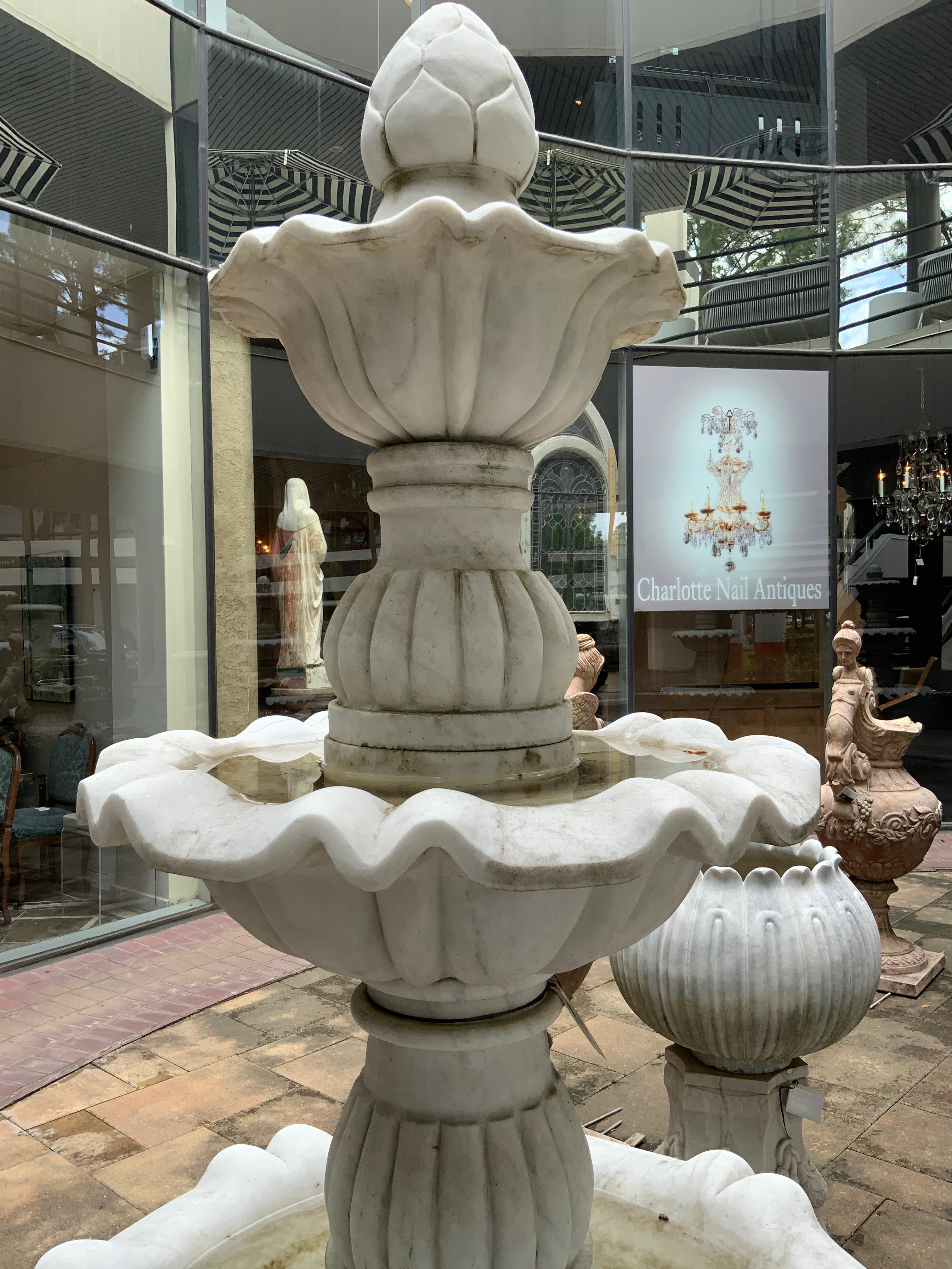 White hand carved marble makes this piece special for your garden.
Three scalloped tiers are graceful and sculpted beautifully.
It ends at the crest with a carved finial. The central post is grooved
For shape and depth. It comes apart for