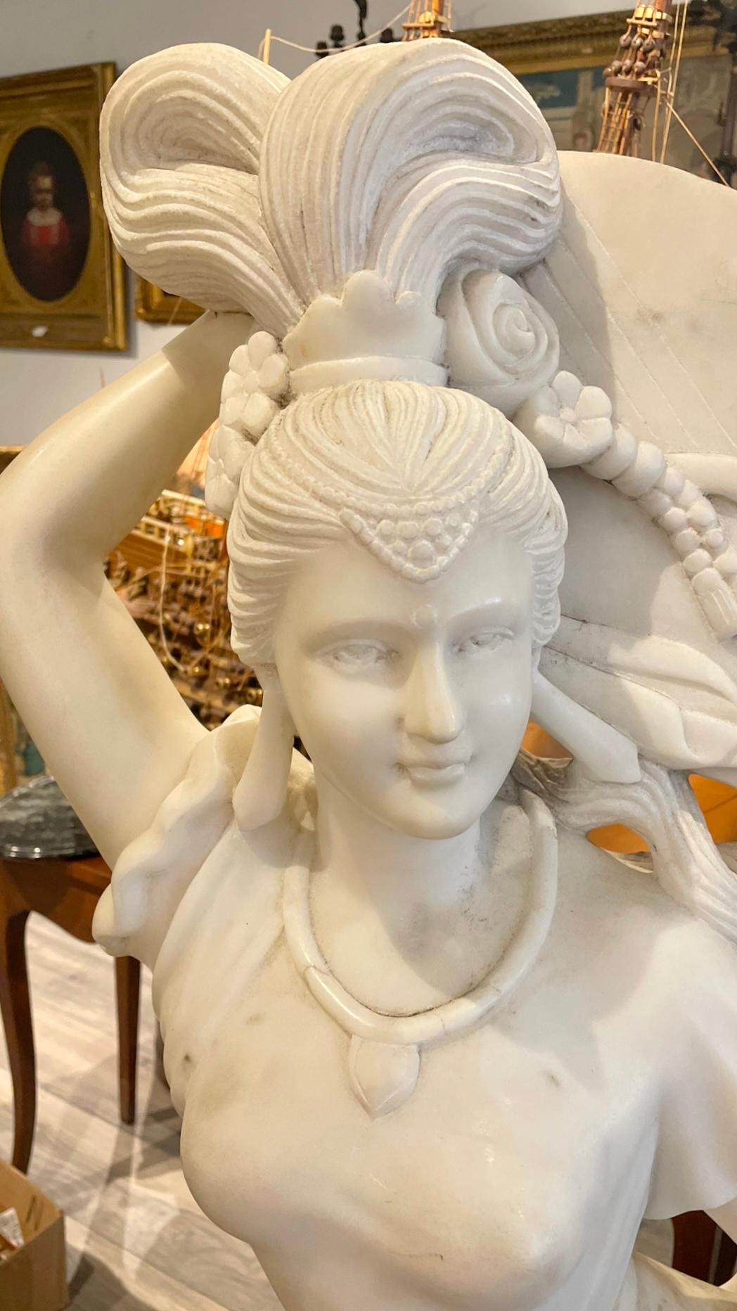 Statua di Apsara volante che suona la pipa, finemente scolpita in marmo bianco, misura 51 per 23 per 25 pollici. Apparentemente non firmato.  In buone condizioni con sporco superficiale, graffi e scalfitture e piccole perdite sparse.

Nel Buddismo,