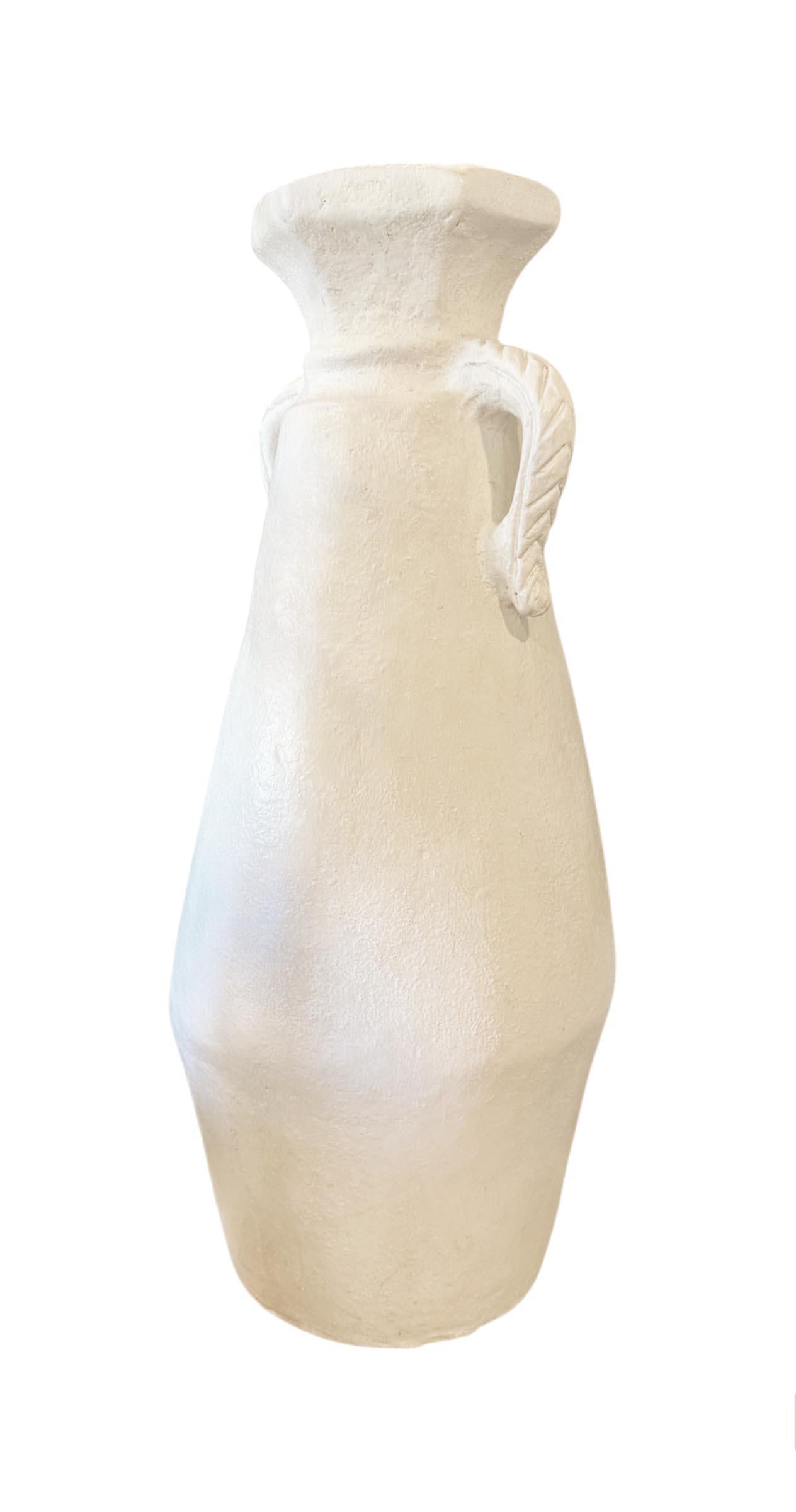 Ce grand récipient en céramique est une pièce intemporelle, parfaite pour ajouter un charme élégant et rustique à n'importe quel espace. Avec son corps gracieusement effilé et son ouverture large et évasée, il est doté de deux poignées sculptées qui