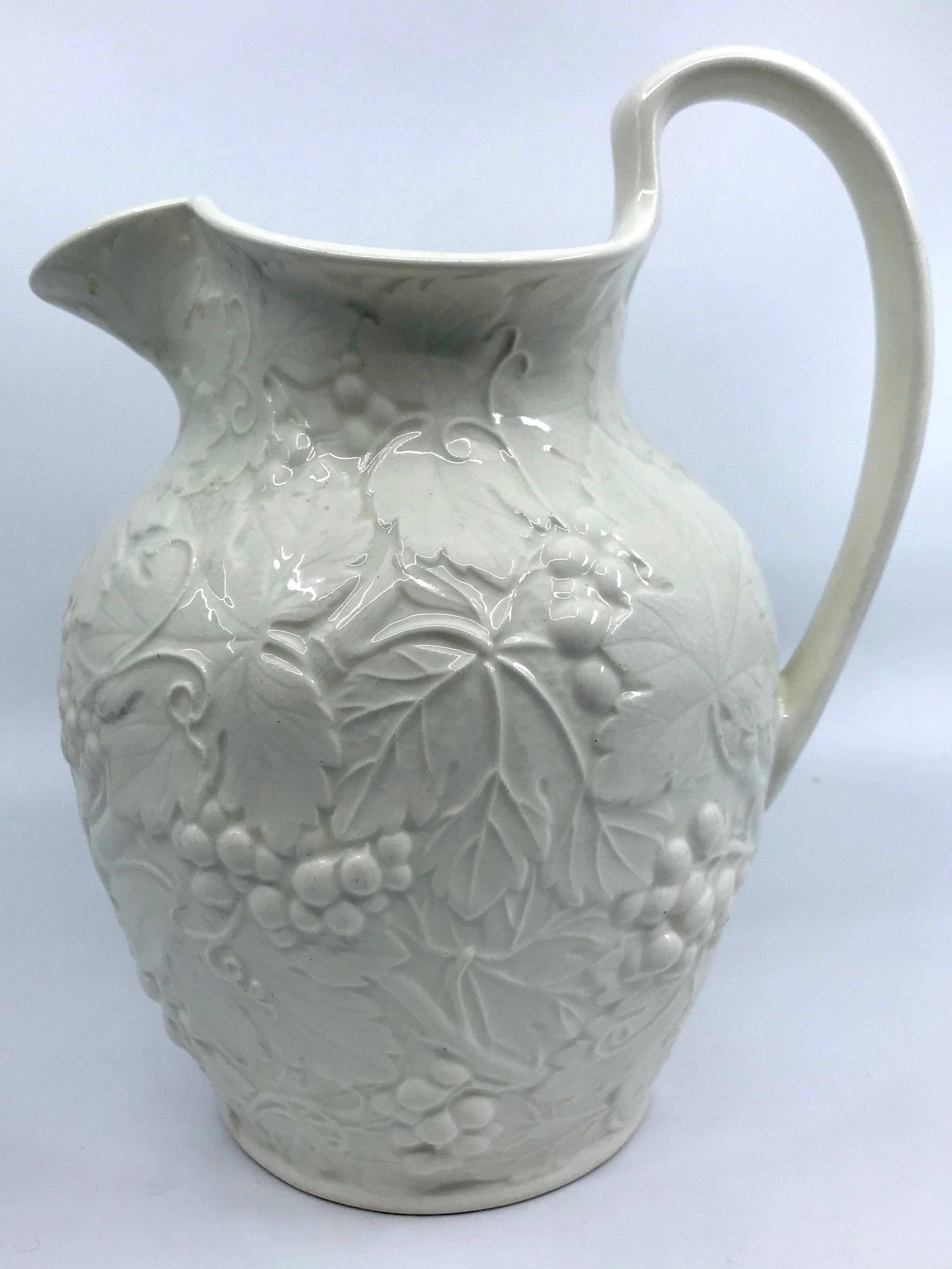 Large white Wedgwood grape-leaf pitcher. Vintage off-white pitcher in an all-over raised grape-leaf and grape cluster design. Green markings for Wedgwood, England circa 1940’s. 
Dimensions: 7.13