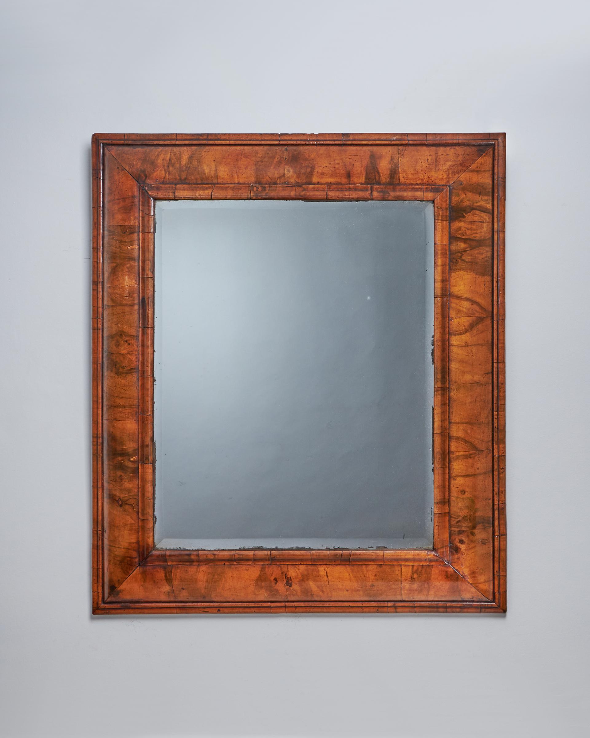 An extremely large and rare William and Mary 17th century figured walnut cushion mirror, circa 1670-1690.

The original soft bevelled edge mirror plate is bordered by fine cross-grain ovolo mouldings. The pulvinated frame is decorated entirely in