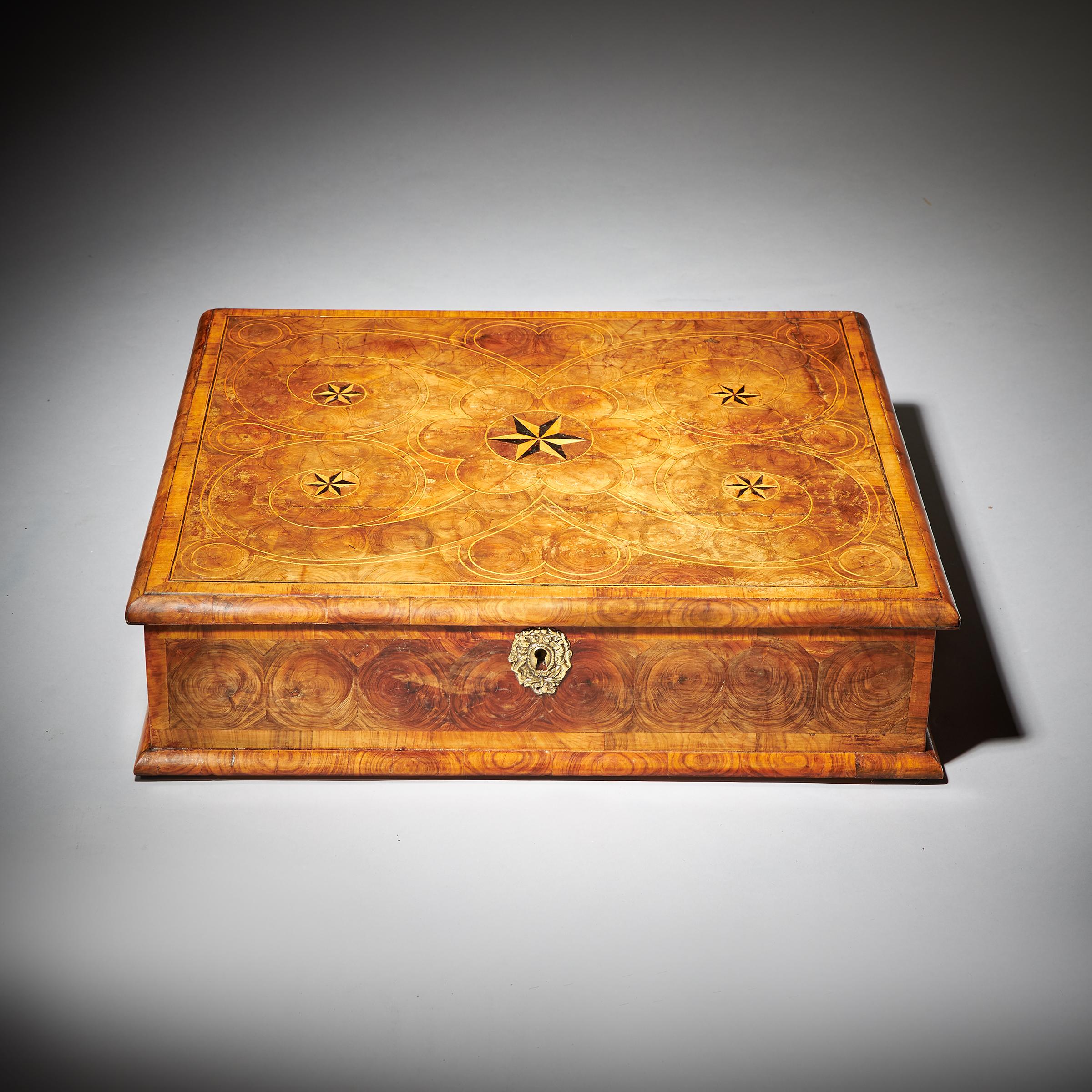 A fine and rare large parquetry inlaid 17th-century William and Mary period olive oyster lace box. 1680-1700, England

The cross-grain moulded top is entirely covered in well-placed oyster of olive in geometric patterns, inlaid with a parquetry