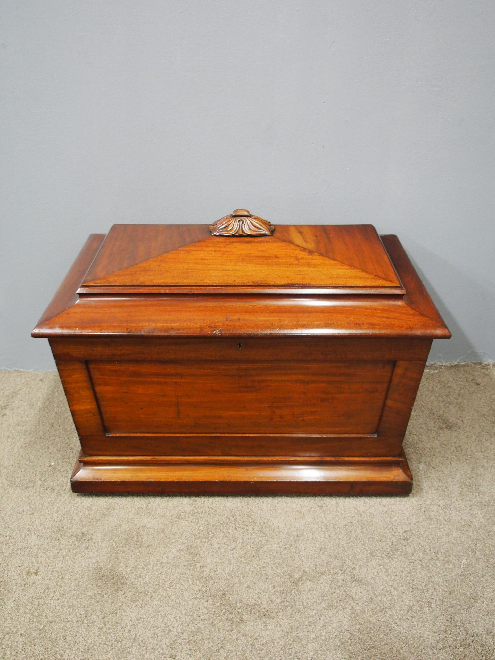 Large William IV mahogany cellarette, circa 1830. The pagoda shaped top with moulded edges, surmounted by an elaborate foliate carving. It has panelled sides with an original brass drainage tap to the rear. It has a moulded plinth base with hidden