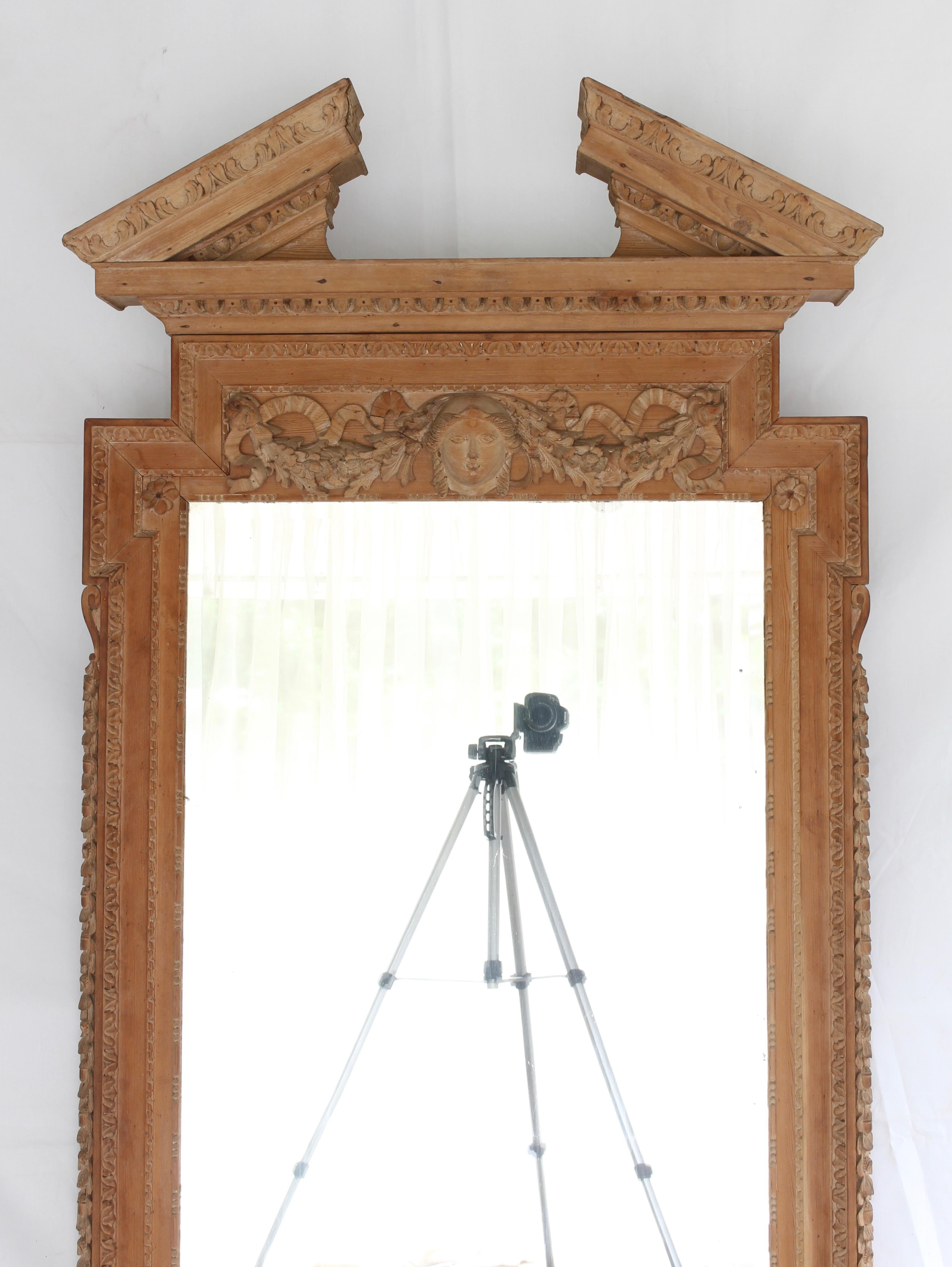 A large and impressive early 19th century heavily carved split pediment pine mirror in the style of William Kent.