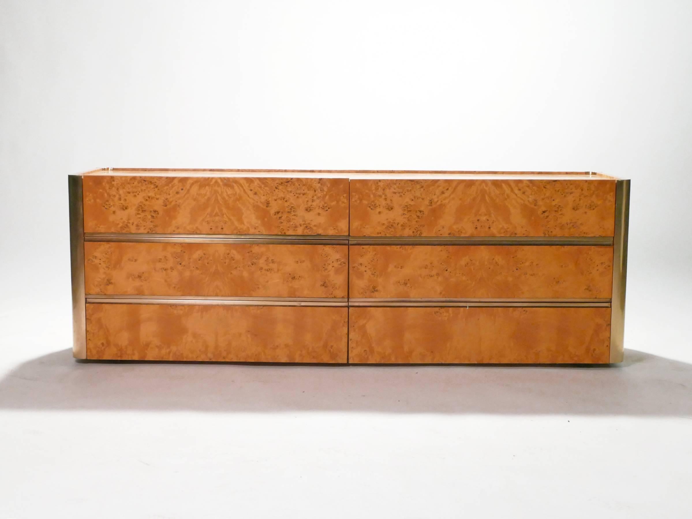 Famed Italian furniture designer Willy Rizzo, known for his luxurious work commissioned by the members of midcentury High Society, created this chest of drawers in the 1970s. The bulk of the piece is a warm burl wood, with brass accents noted
