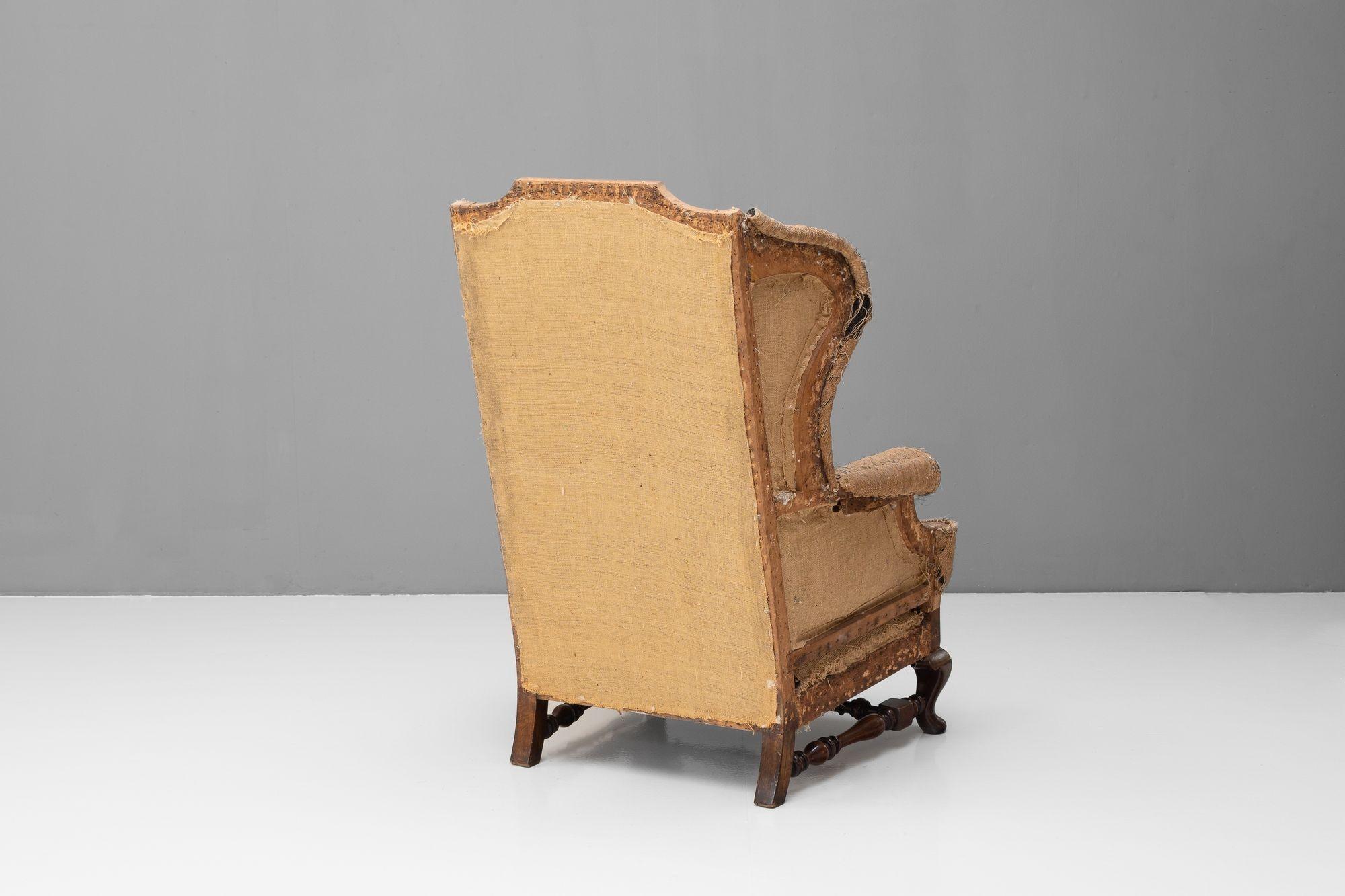 Large wing chair on cabriole legs united by turned stretchers. Circa 1890.

H 115cm (SH 45cm) x W 63cm x D 80cm