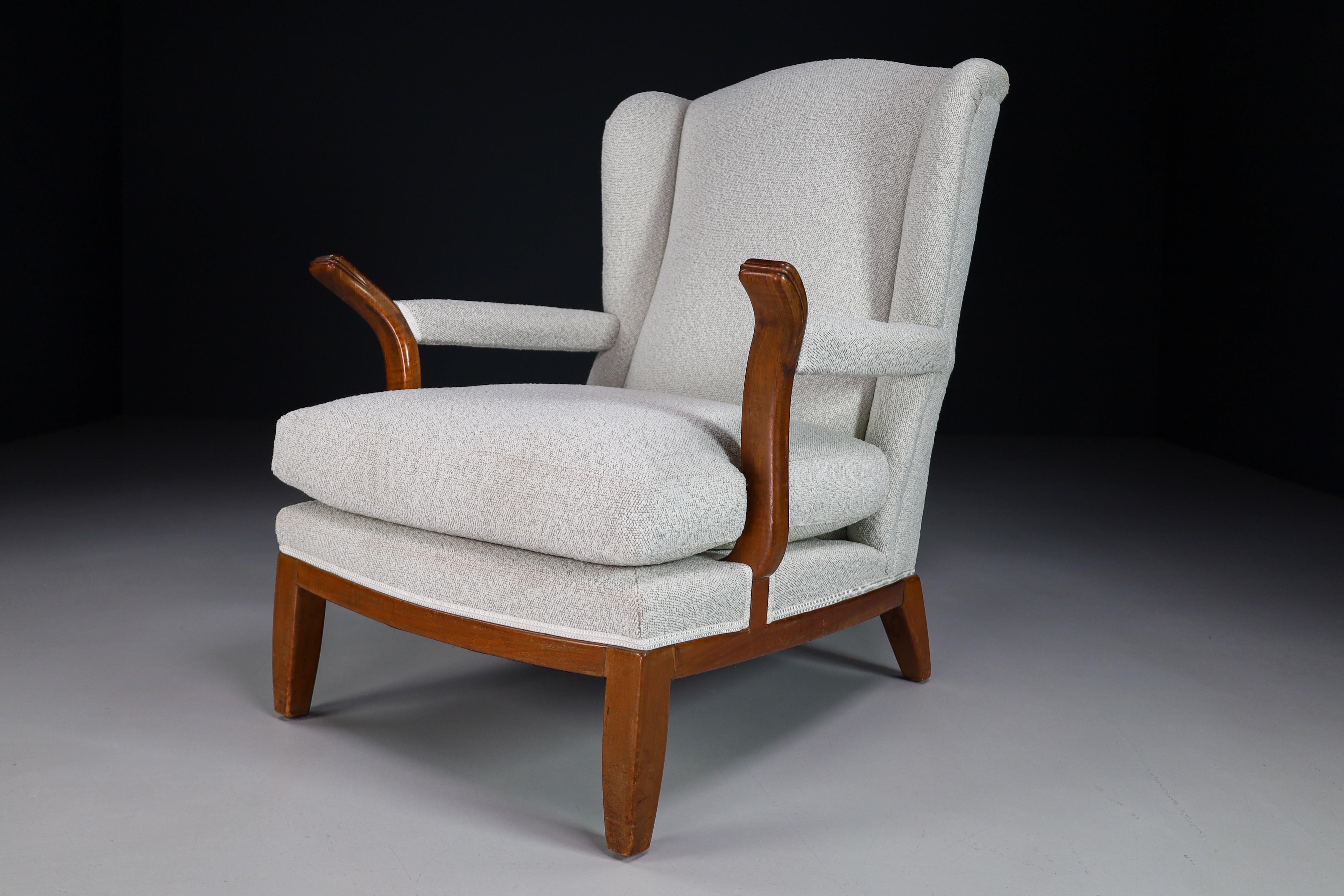 Chaise à oreilles de grande taille fabriquée et conçue en France dans les années 1930. Fabriquée en noyer, la chaise à oreilles vient d'être retapissée avec un tissu en laine Bouclé. Il est en parfait état, petite patine sur les parties en bois. Ce