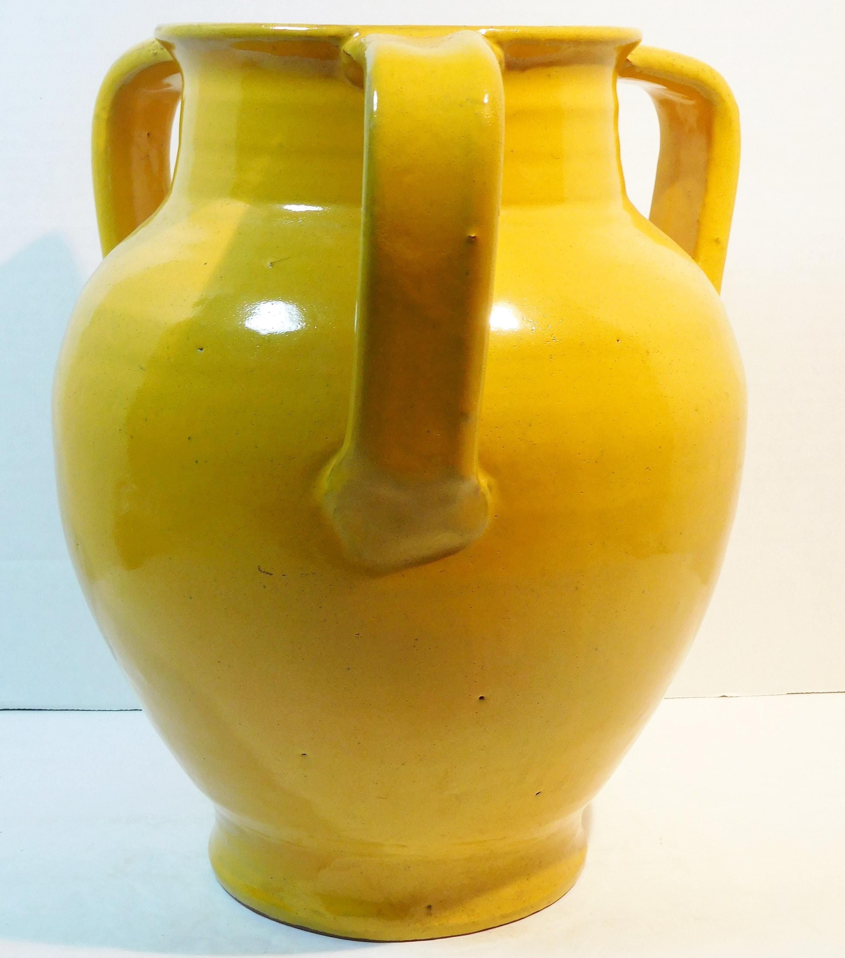 This large table vase made from red clay has a Chinese yellow glaze and three applied handles. On the bottom, it has unravelled-screen-wire marks which reveal its age since this technique of cutting the pot from the throwing wheel was used by North