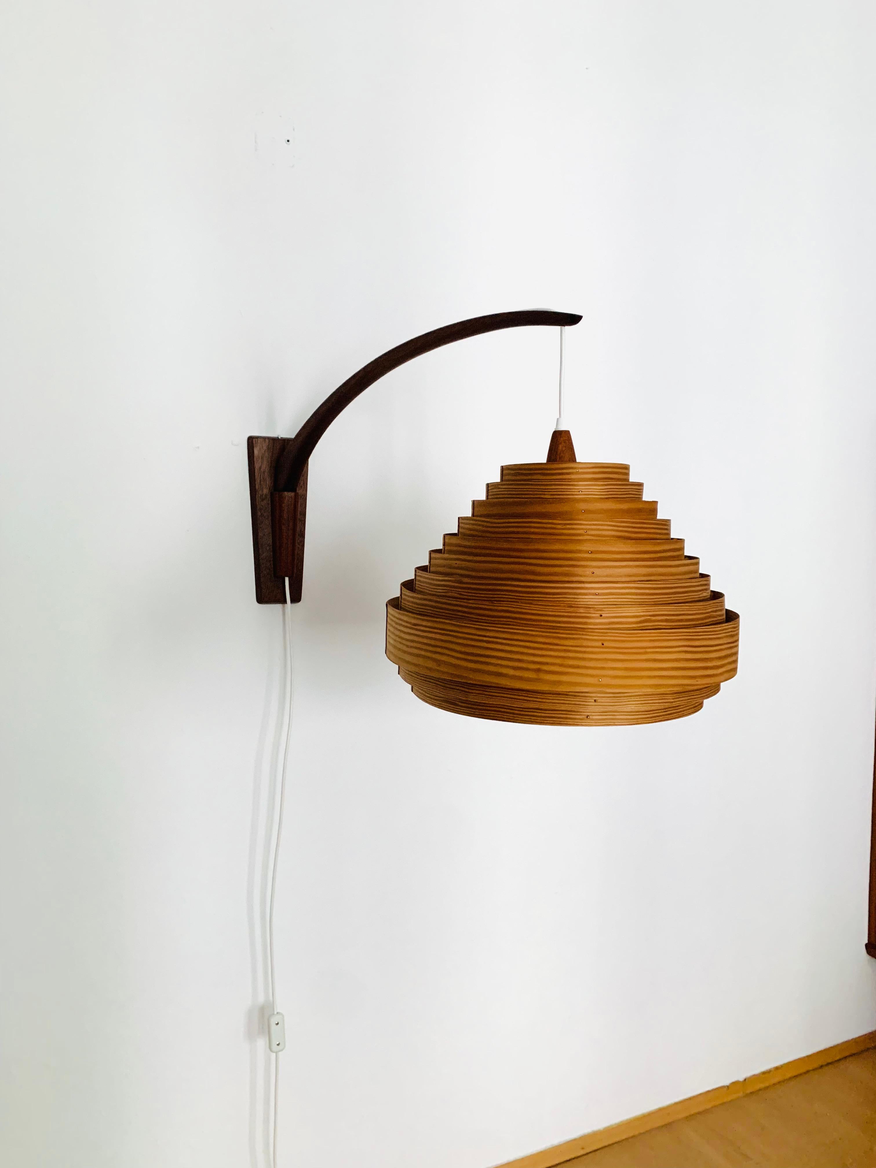 Very large teak wall lamp from the 1960s.
Great and unusual design with a fantastically elegant appearance.
Very nice swiveling teak arm.
The pine wood lampshade creates a spectacular play of light and creates a very cozy