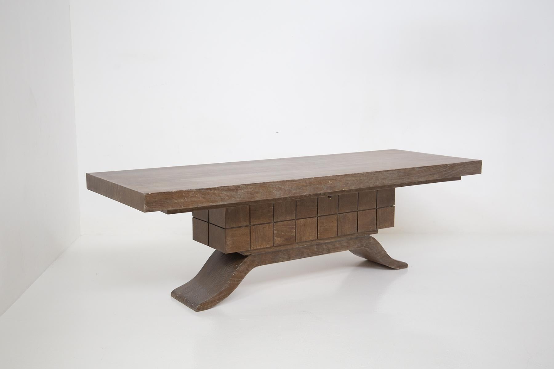 Large dining table attributed to Guglielmo Ulrich made entirely of wood. The table has a central rectangular pedestal with square carvings. The feet are made of sinuously curved wood almost representing a semi-corner.
The table comes from a