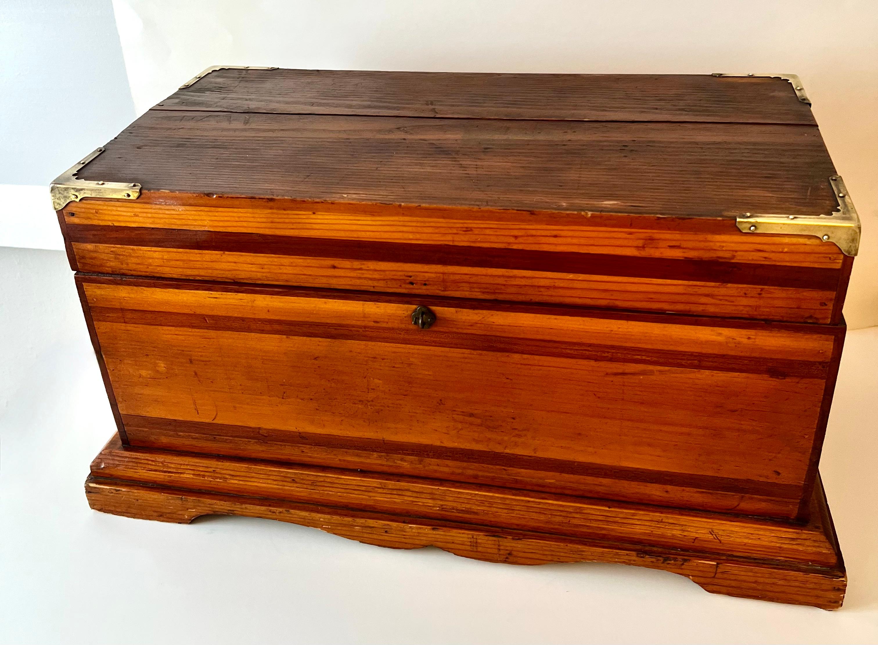 Wooden had made box with brass top corners - decorative and great storage too... The use of multiple woods and interesting base makes this piece a great addition to any counter, shelf or console. 

A compliment to a rustic environment or