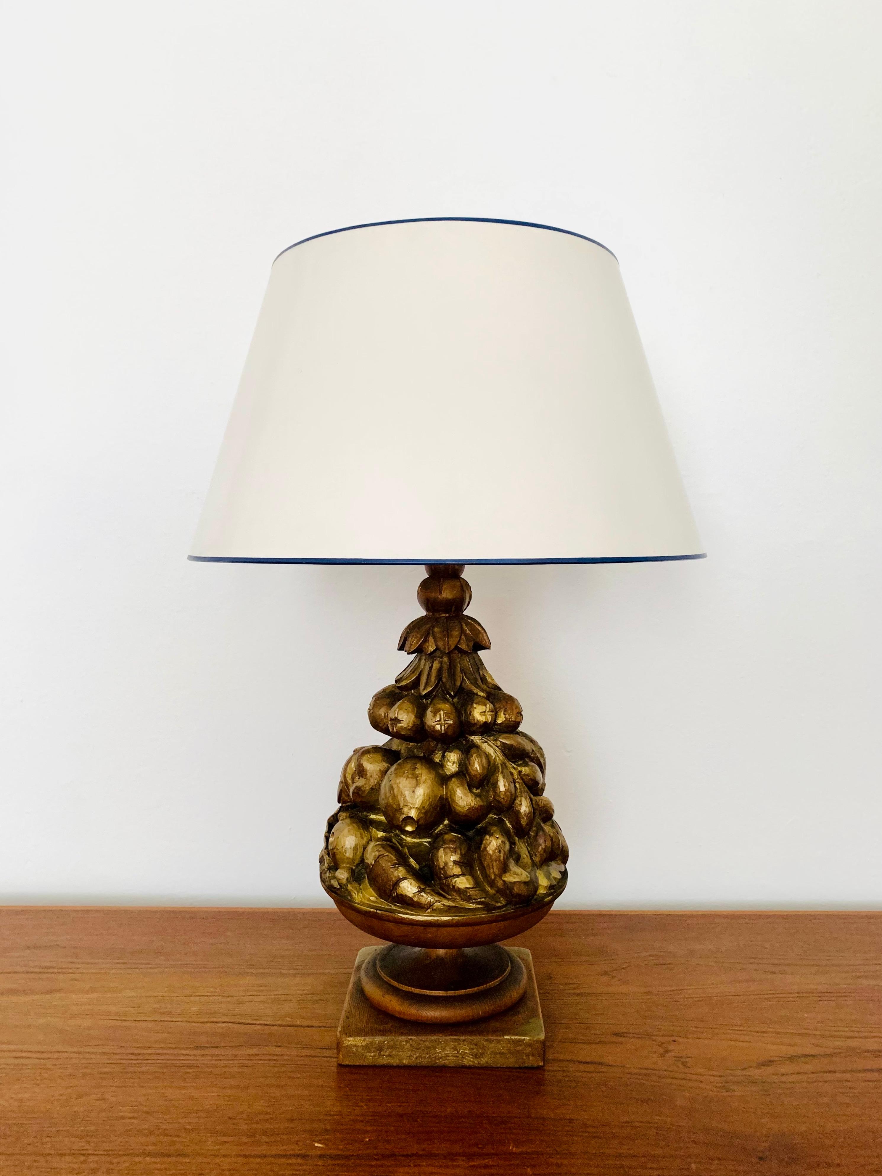 Very nice large table lamp from the 1970s.
Great design and high-quality workmanship.
The wooden base is richly decorated with carvings in fruit decor.
The surface is gilded in places.
A wonderful light emerges.

Condition:

Very good vintage