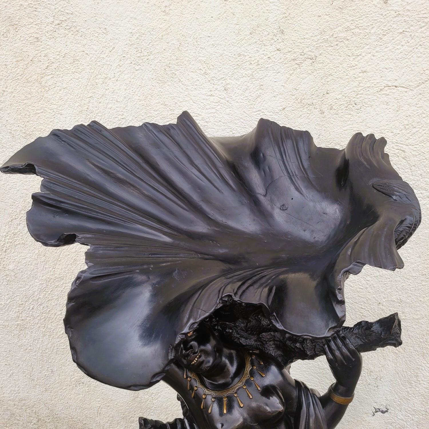 Grande sculpture en bois teinté noir représentant une femme maure portant un coquillage, un dragon à ses pieds.   

Les yeux et les dents sont en nacre.   

Quelques manques (queue de boucher), usures, fissures et restaurations anciennes. 

 Œuvre