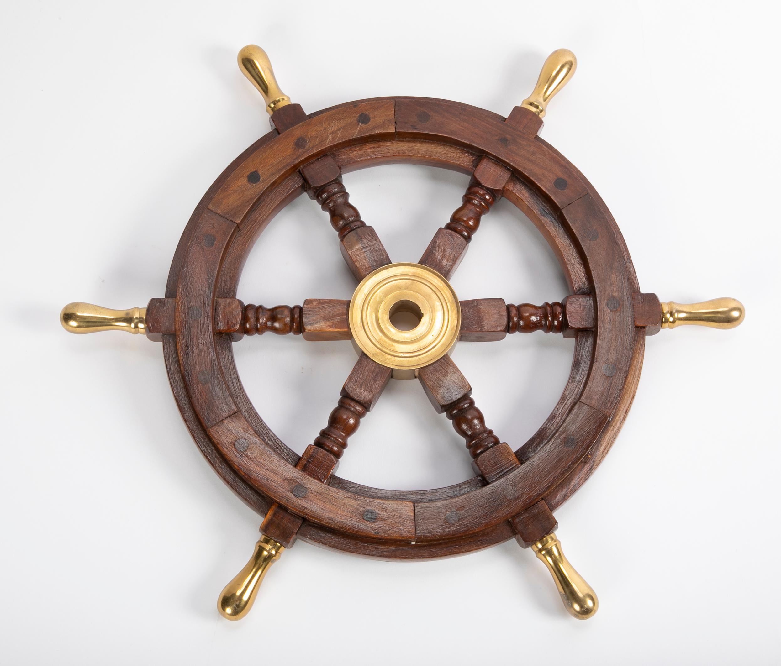 A large early 20th century wooden ship's wheel with brass accents.