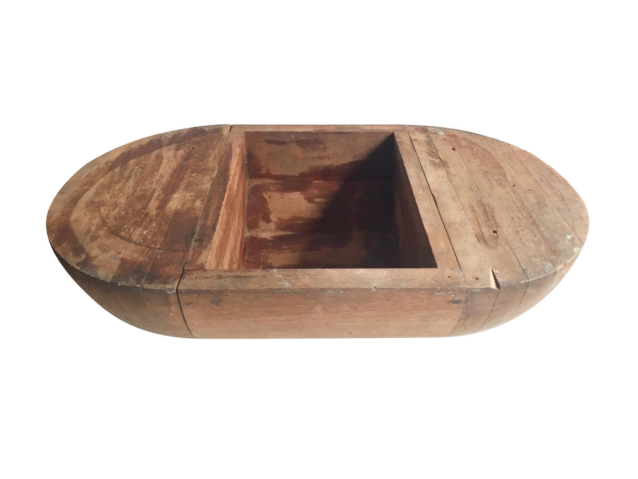 A large handmade wood trencher bowl, early 20th century. It is a pill-like oval shape with a curved underside and a flat top. Made from substantial hardwood, the bowl is a sturdy, quite heavy container that can be used as a decorative centerpiece or