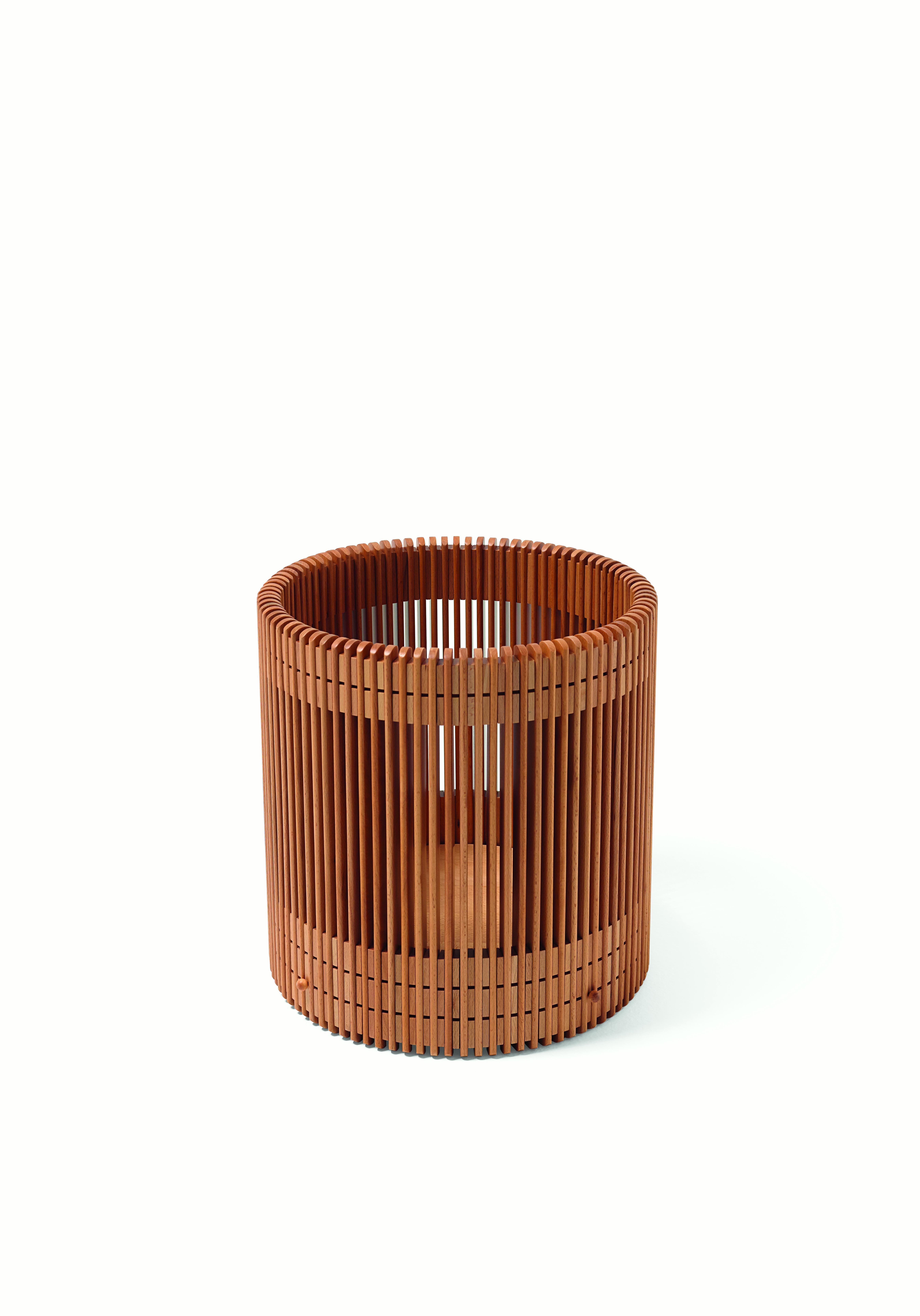 A wastepaper basket made of 89 beechwood baguettes connected by 178 spacers. The vertical elements, individually polished to obtain a total flattening of any edges, are connected by four circles. The bottom is fixed through brass pivots, whose