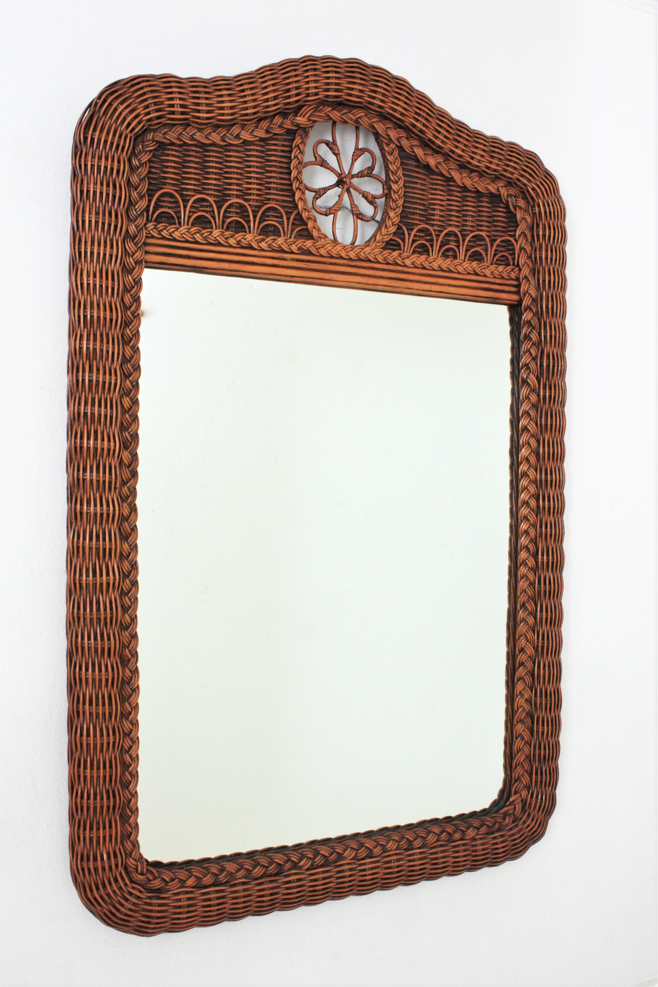 Eyecatching woven rattan large mirror with crest. Spain, 1970s.
This beautiful wall mirror or console mirror features a thick frame made of braided rattan. The arched top is adorned by a flower decorative detail.
This mirrow will be a nice addition