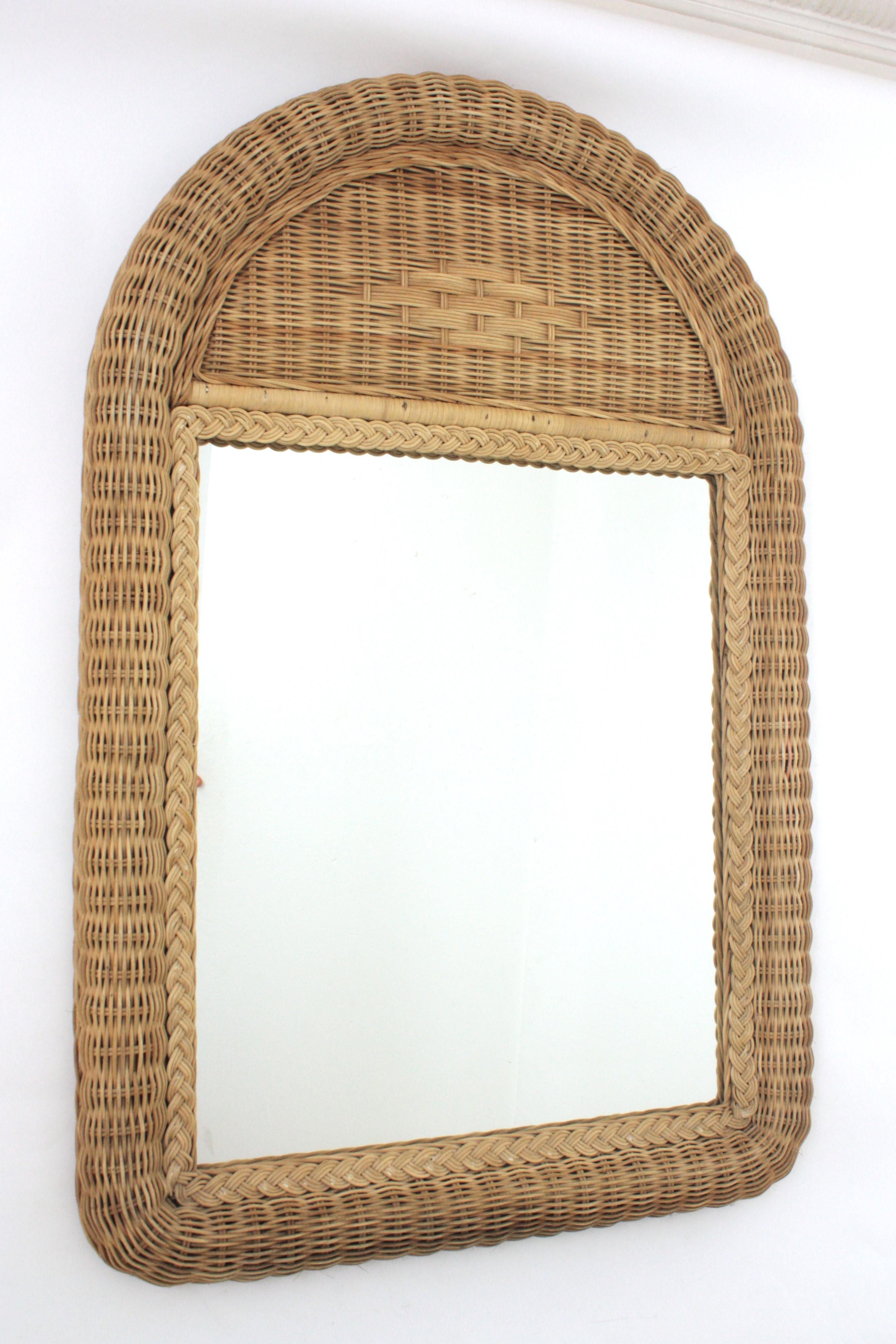 Accattivante specchio grande in rattan intrecciato con piano ad arco. Spagna, anni '70.
Questo bellissimo specchio da parete o da console è caratterizzato da una spessa cornice in rattan intrecciato. La parte superiore ad arco è ornata da un