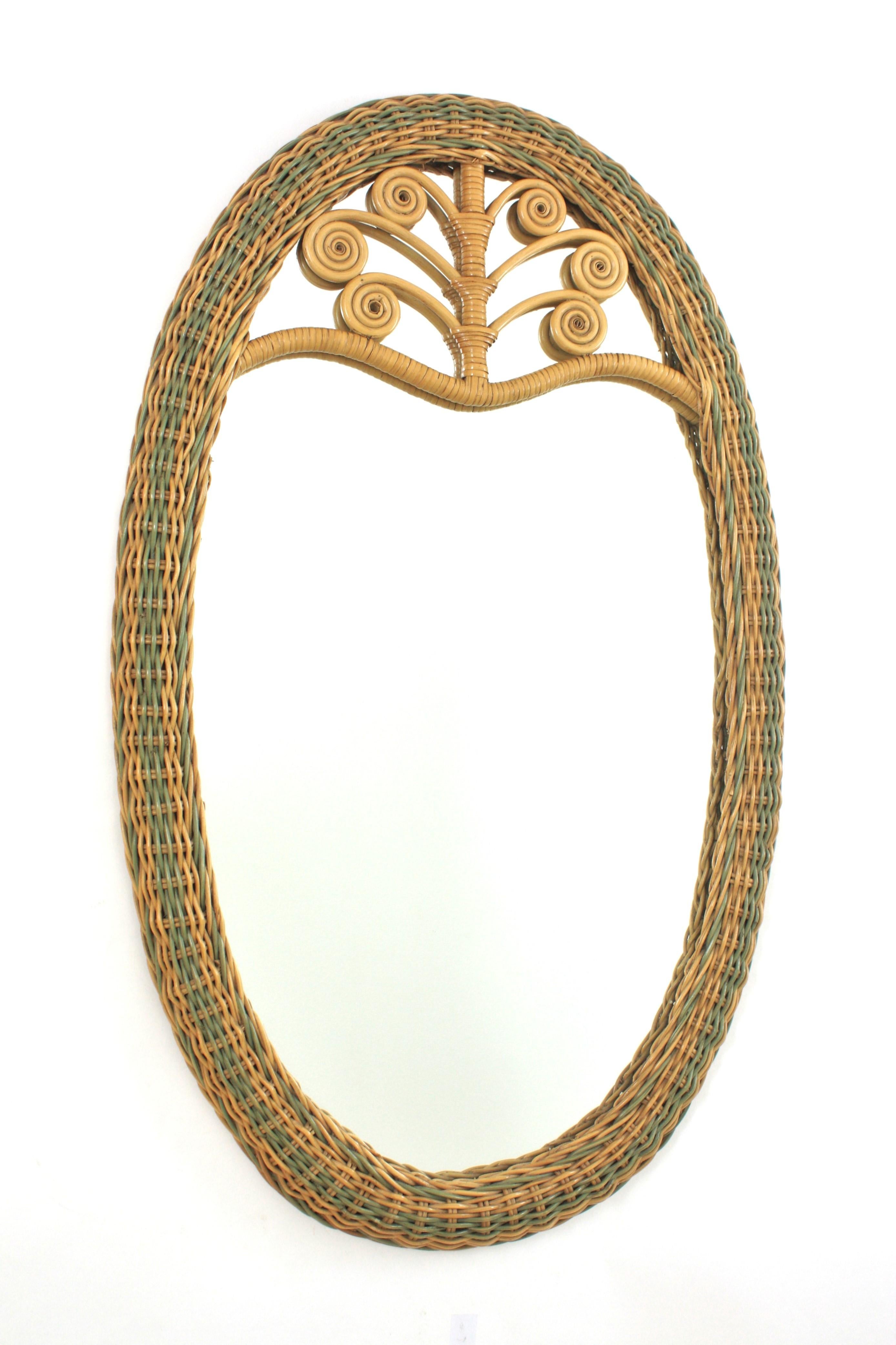 Specchio ovale intrecciato a mano in rattan bicolore 
Accattivante specchio in rattan bicolore intrecciato con decorazioni in filigrana sulla parte superiore. Spagna, anni '60
Questo bellissimo specchio da parete o da console è caratterizzato da una