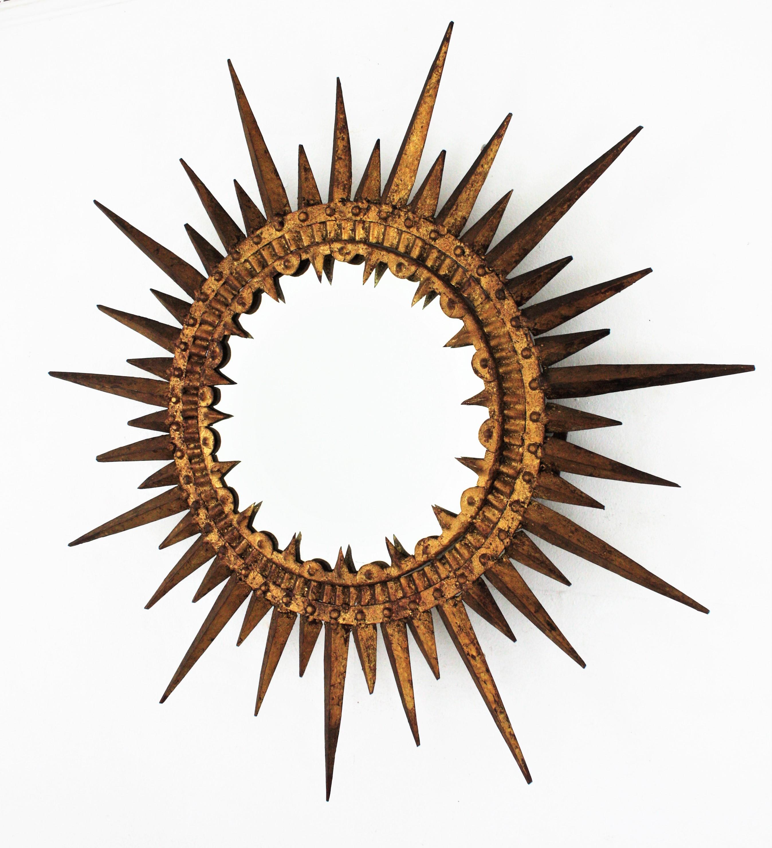 One of a kind wrought iron gold leaf gilded sunburst mirror, Spain, 1950s.
This hand-hammered sunburst mirror has a extremely detailed hammered work and was made entirely by hand. The sun shaped frame is richly adorned by pointed rays, nails