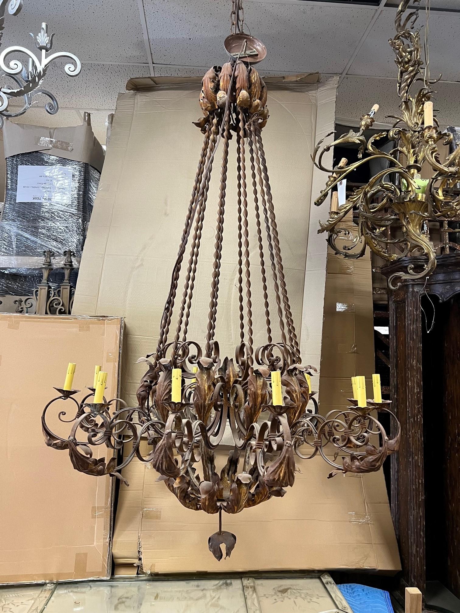 This is a great large iron chandelier with twisted wrought iron rods and acanthus leaves on a rustic chandelier. Handmade with 12 lights, electrified and a great size 4' x 6' and I believe it was made in the USA maybe 20 years ago. It is ready to