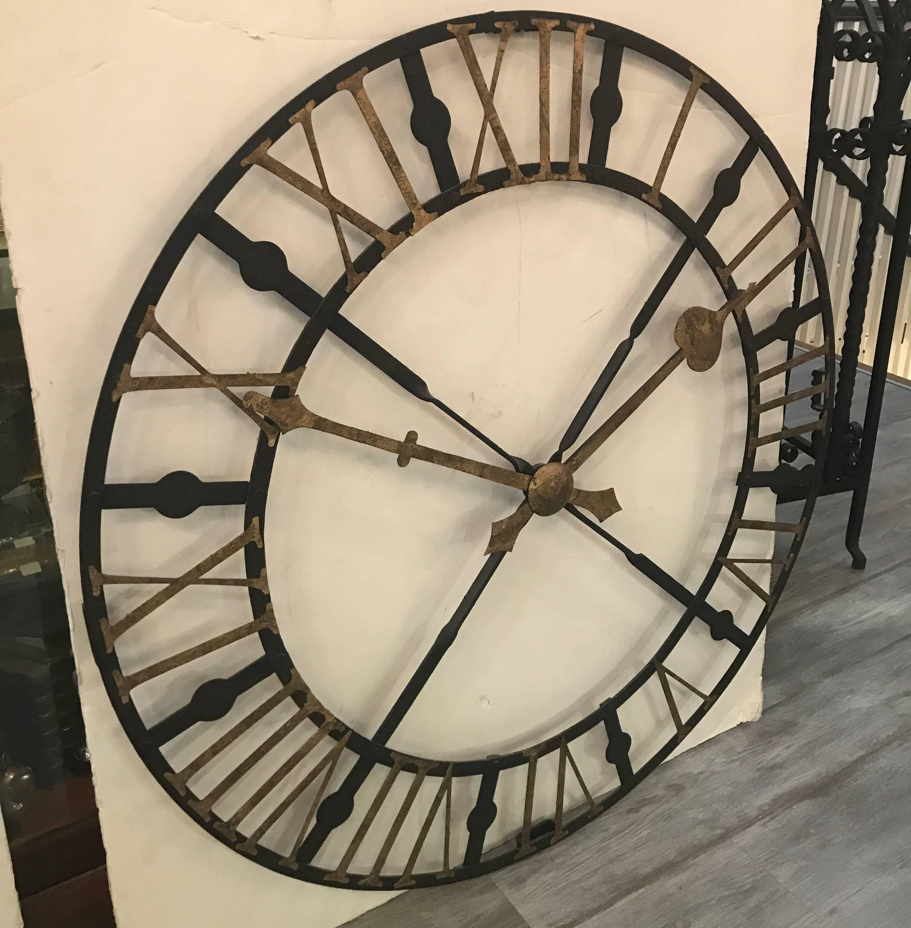 Large weather iron 42 inch clock face with roman numerals. This is a decorative wall decoration with gilt numerals, hour and minute hand that is not a time piece. The hands are stationary. The weathered iron finish is intentional.