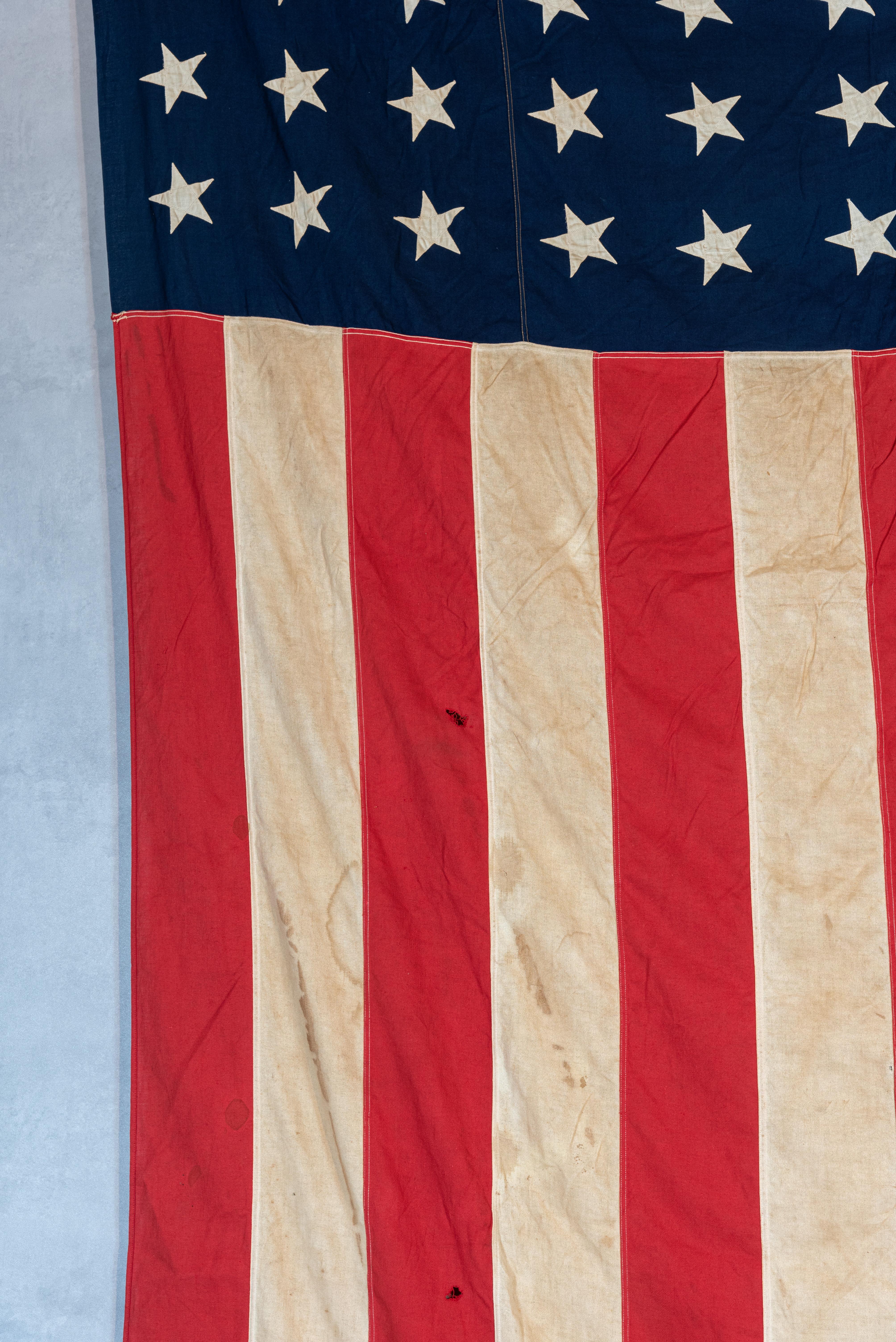 Step back in time and immerse yourself in the history of World War II with this remarkable and very large American flag made by Defiance. This flag, dating back to the WWII era, is believed to have been used in 1944, adding a sense of authenticity