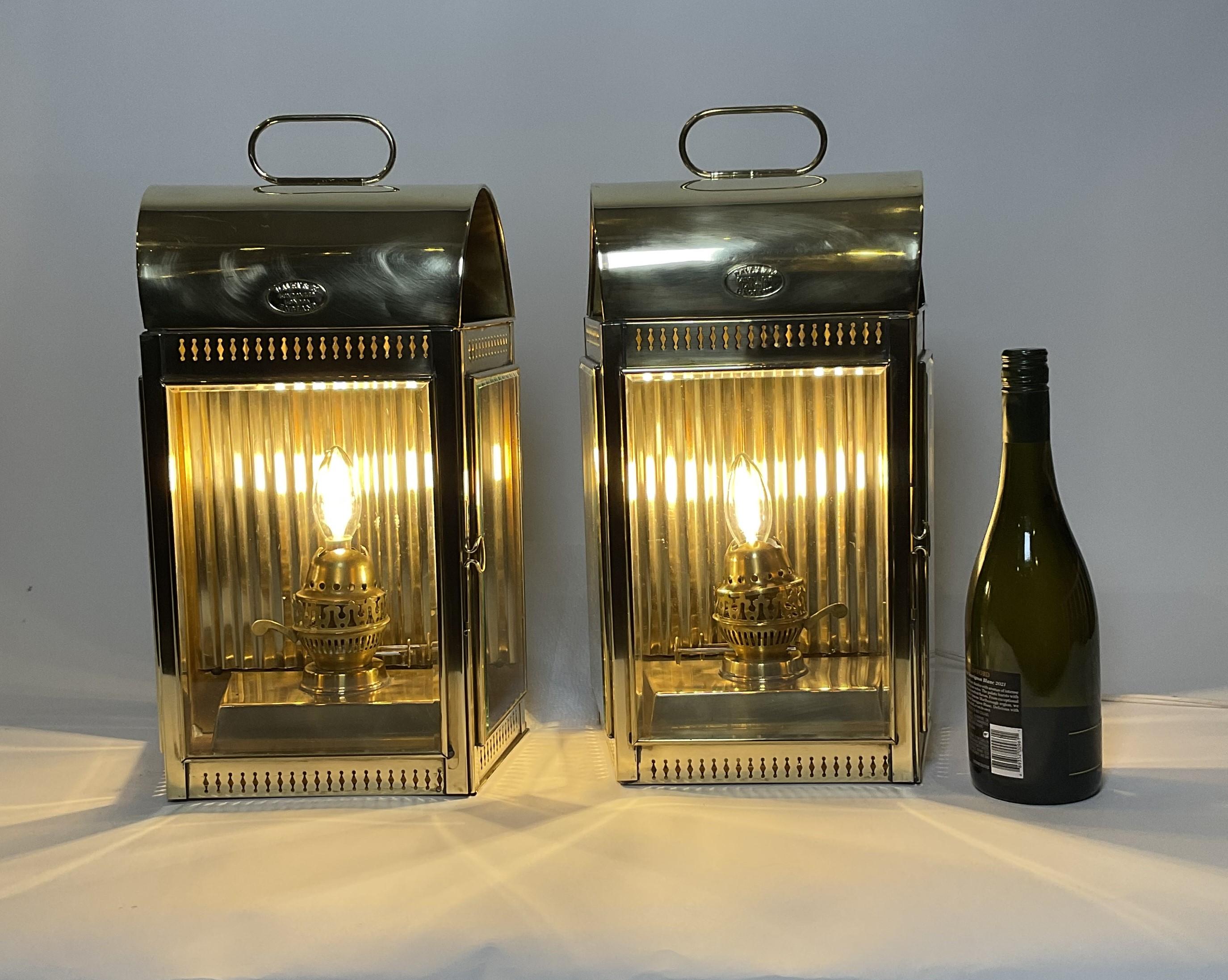 Solid brass ships cabin lanterns by Davey of London. Exceptionally large examples from Davey with three beveled glass windows, hinged doors, vented tops, carry handles. Both have house mounting brackets. Highly polished. Perfect for the front of a