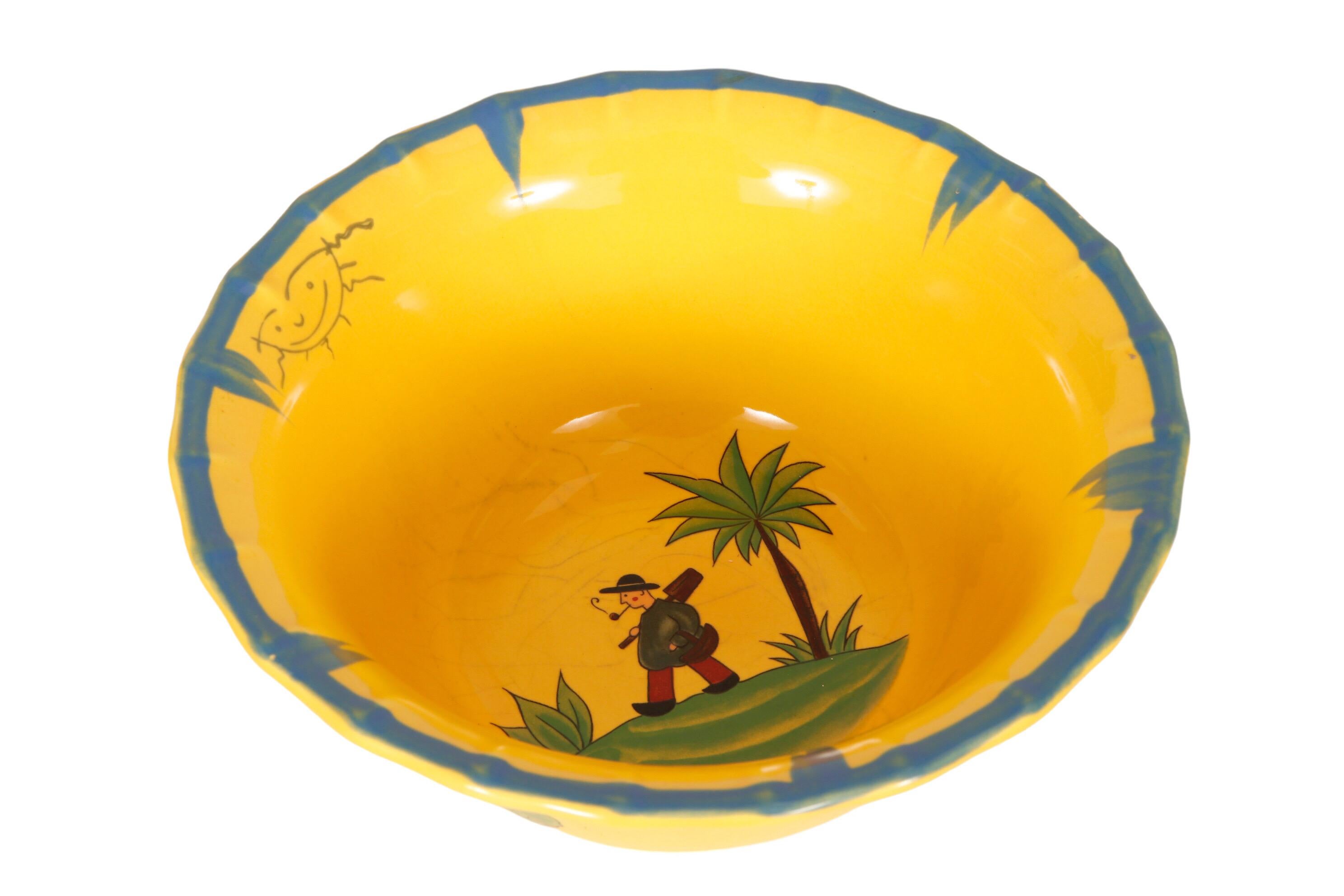 A large yellow ceramic bowl made by The Haldon Group. Decorated in the center with a simple walking figure smoking a pipe, reminiscent of the French Quimper Hiker. The rim of the bowl is edged in blue with a smiling sun. On the outside is a
