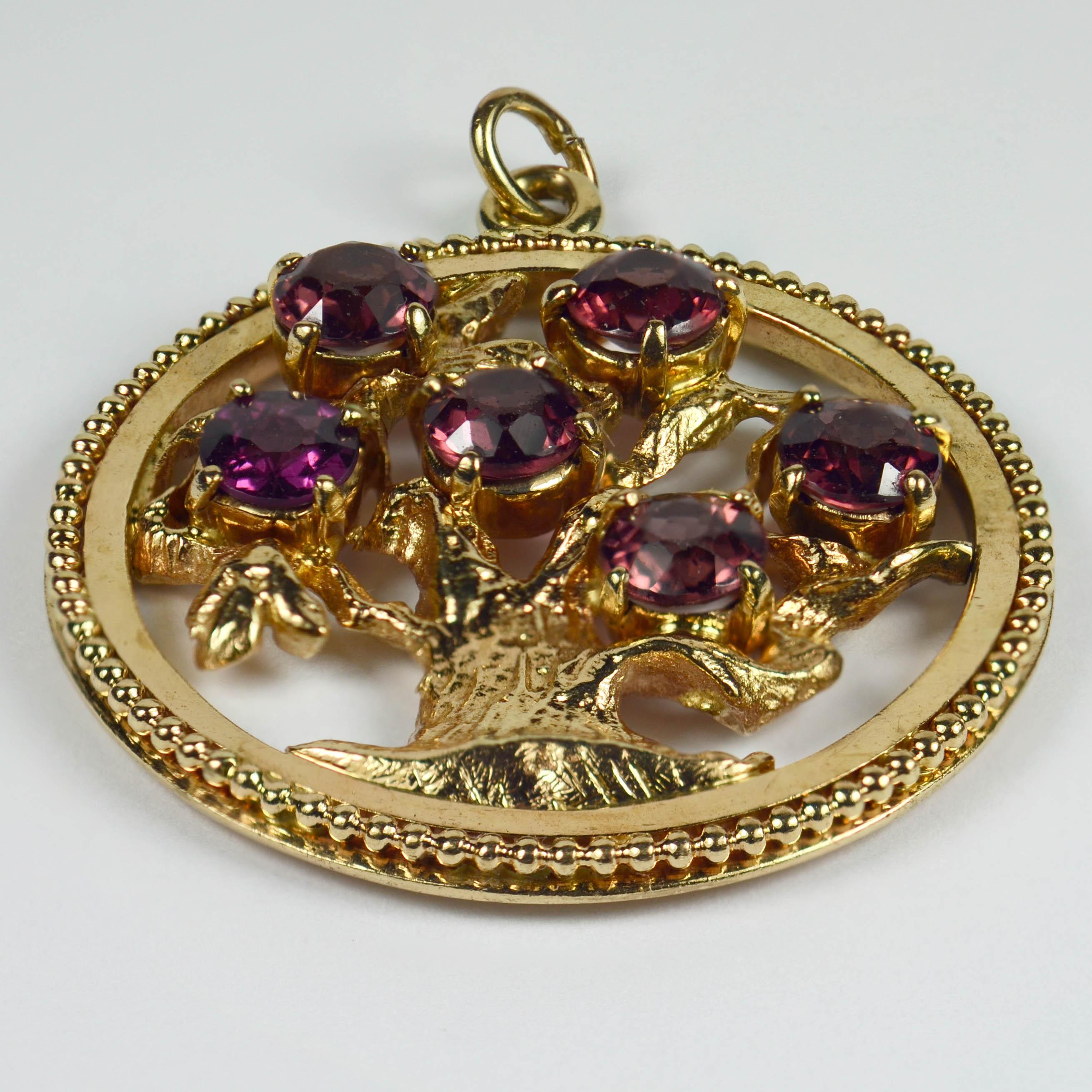 A large 14 karat yellow gold charm pendant designed as an open medallion with beaded edge, depicting a tree of life set with six red garnets, each weighing approximately 1 carat. Stamped 14K for 14 karat gold and American manufacture.

Total gem