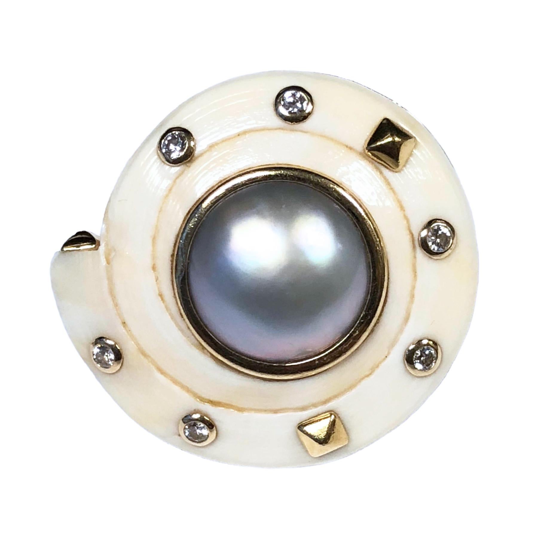 Circa 1970s 14K Yellow Gold and White Coral Earrings in a Nautical shell design, measuring 1 1/4 inches in diameter, centrally set with a 12 MM Grey Mabe pearl and further set with Round Brilliant cut Diamonds totaling 1/2 Carat. Omega Clip backs to
