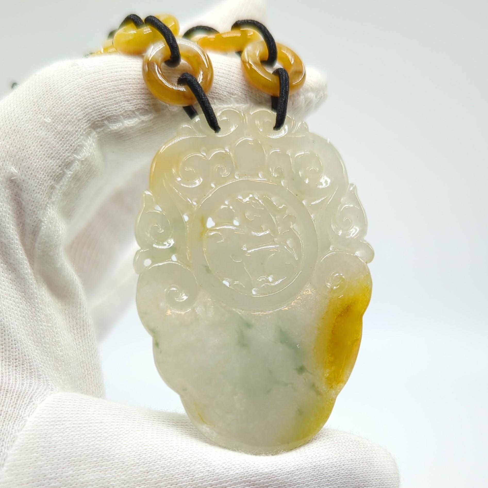 A large finely carved and pierced natural yellow jadeite pendant, featuring a circular medallion, surrounded by scrolling foliage borders (L:22-28