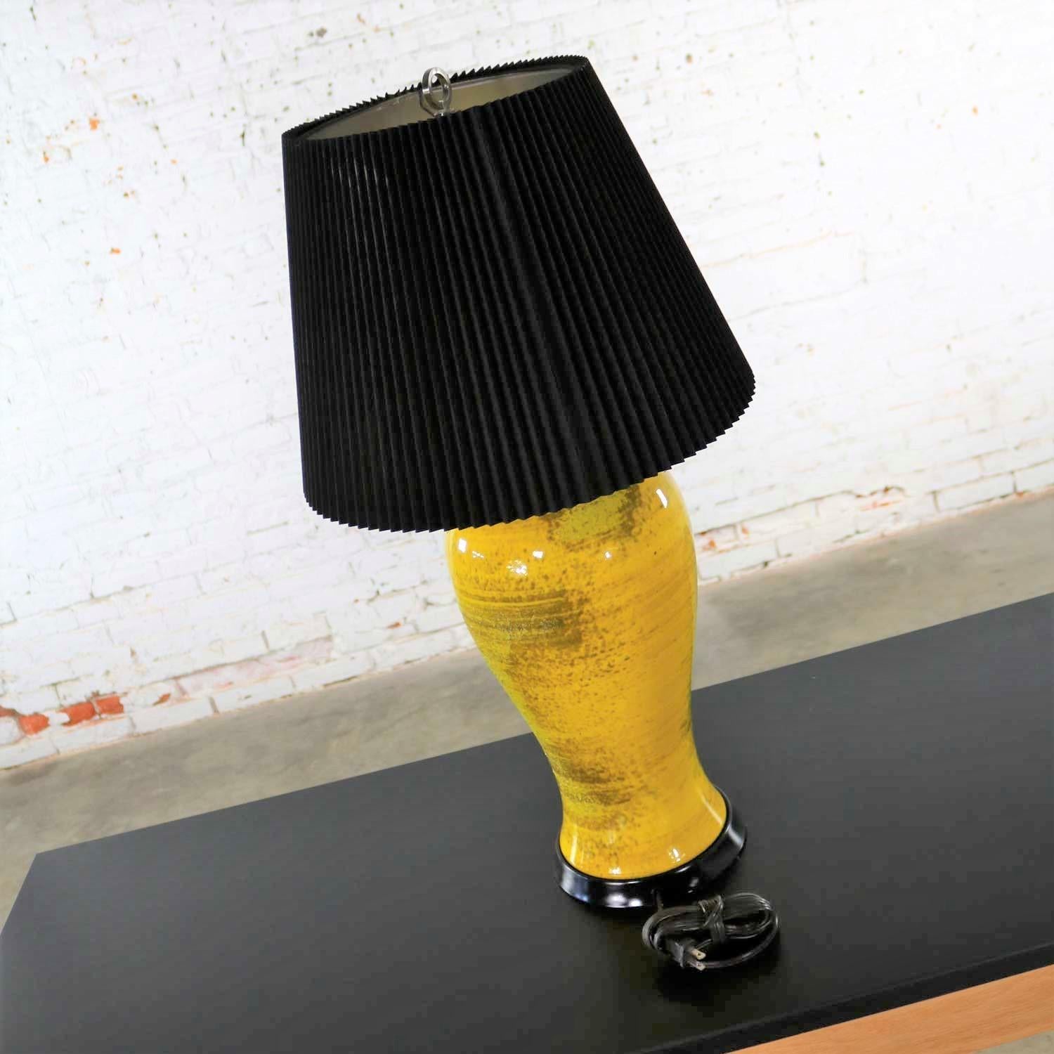 An amazing Mid-Century Modern large almost monumental sized lamp with a sunflower yellow ceramic with partial lava glaze urn shaped base and a black pleated shade. It is in wonderful vintage condition. The foot has been restored and repainted and we