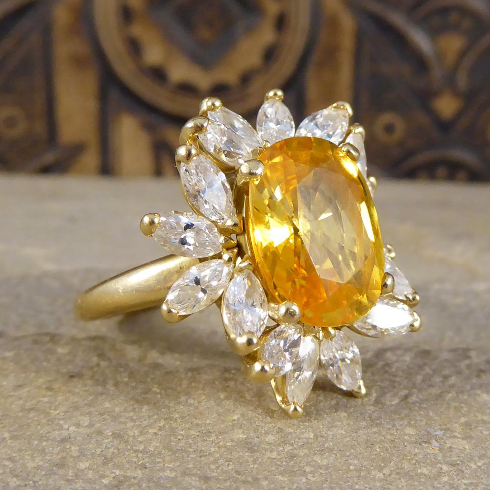 Big, bright and colourful with a 5.75ct cushion cut Yellow Sapphire in the centre. This ring also has Marquise cut Diamonds set around the Sapphire weighing 2.4ct in total, placed in a way to create a fiery flower cluster aesthetic. All set in 18ct