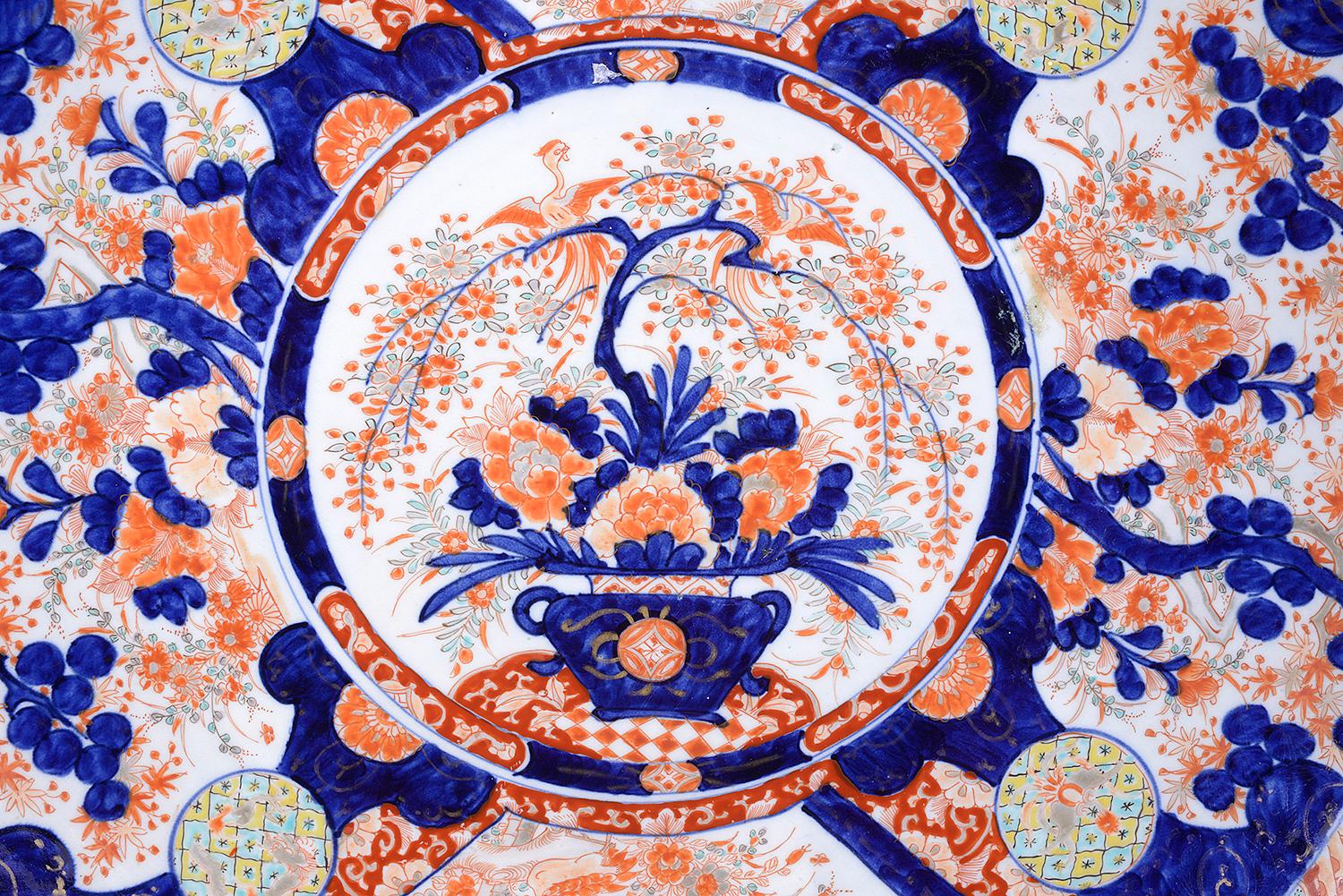 A good quality 19th century Japanese Imari charger, having the typical blue and orange grond colors, having segmented painted inset panels with floral and classical motif decoration, the circular central panel depicting a jardinière, full of fruit,