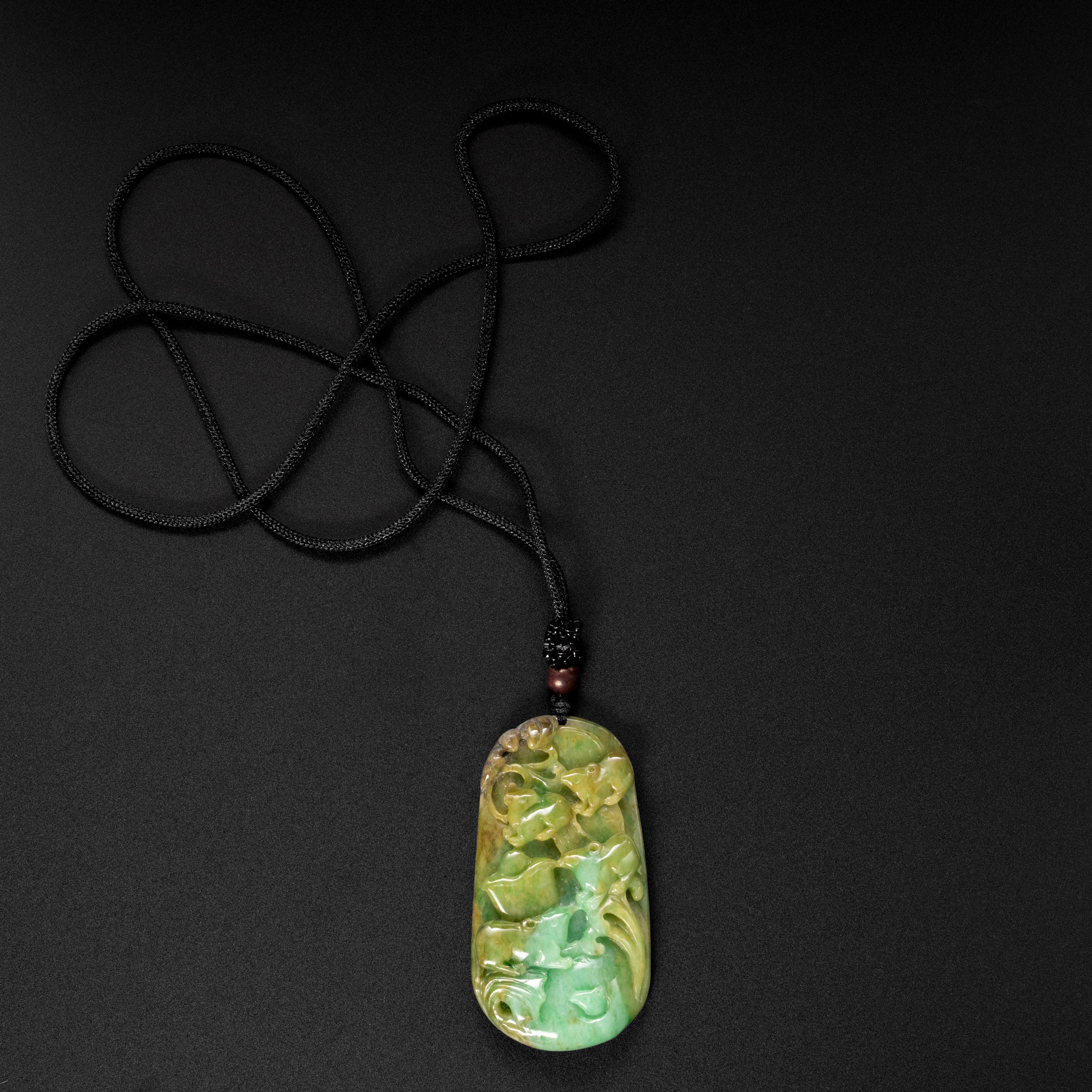 This lush and verdant pendant has been skillfully and recently carved with auspicious symbology. The large (63.37mm x 34.16mm x 10.78mm) oval carving displays a range of luscious green tones; from light sage to that beautiful bluish-green of