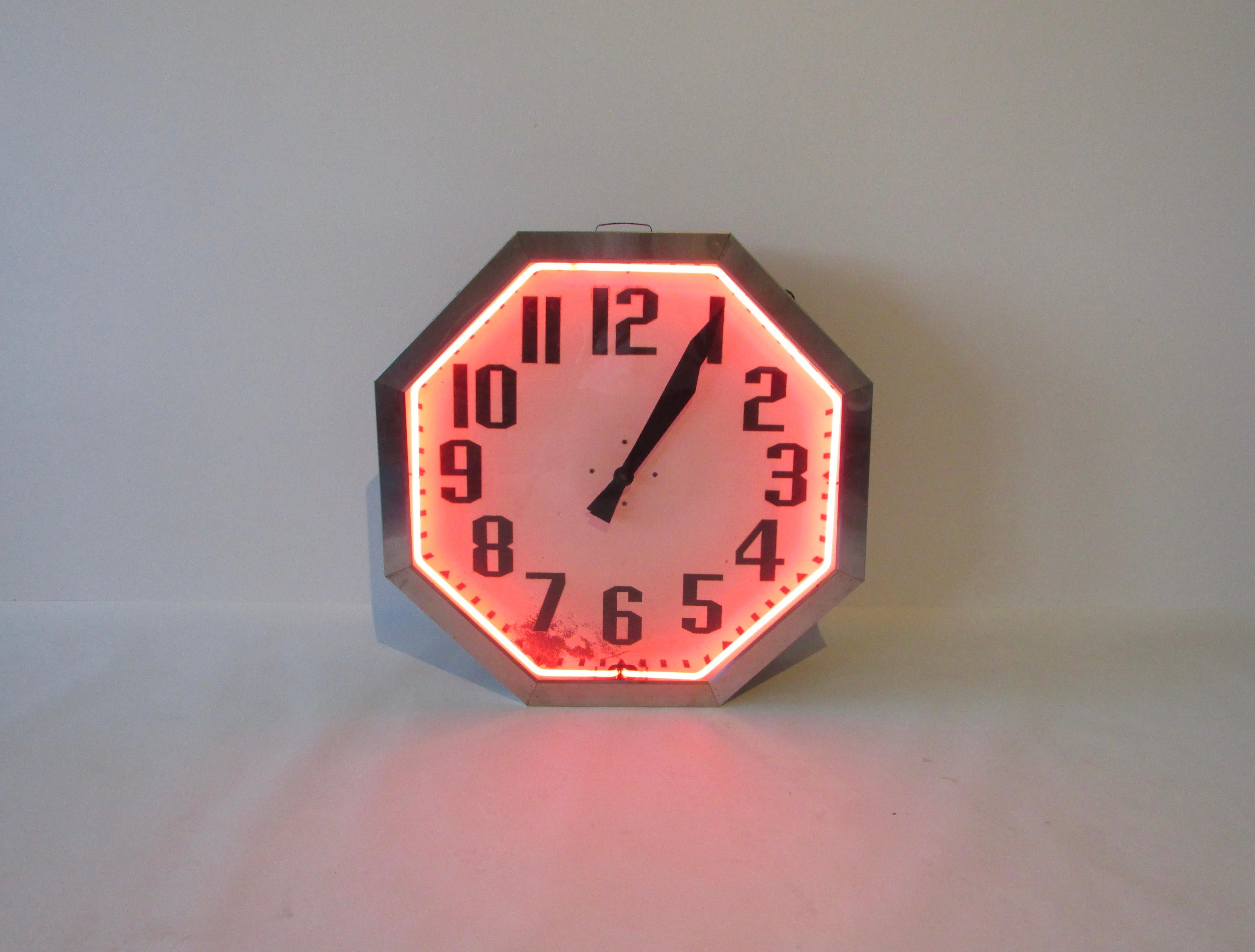 Large octagon form neon clock. Trimmed in stainless steel. Appears to have been an indoor clock. No rust or weather damage. Minor paint loss to face.